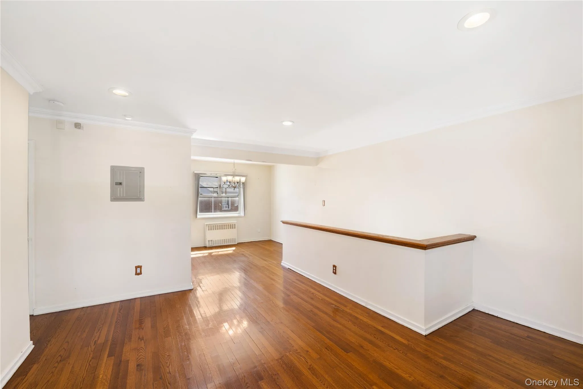 Unfurnished room featuring dark wood finished floors, ornamental molding, recessed lighting, a chandelier, and radiator Unfurnished room featuring dark wood finished floors, ornamental molding, recessed lighting, a chandelier, and radiator