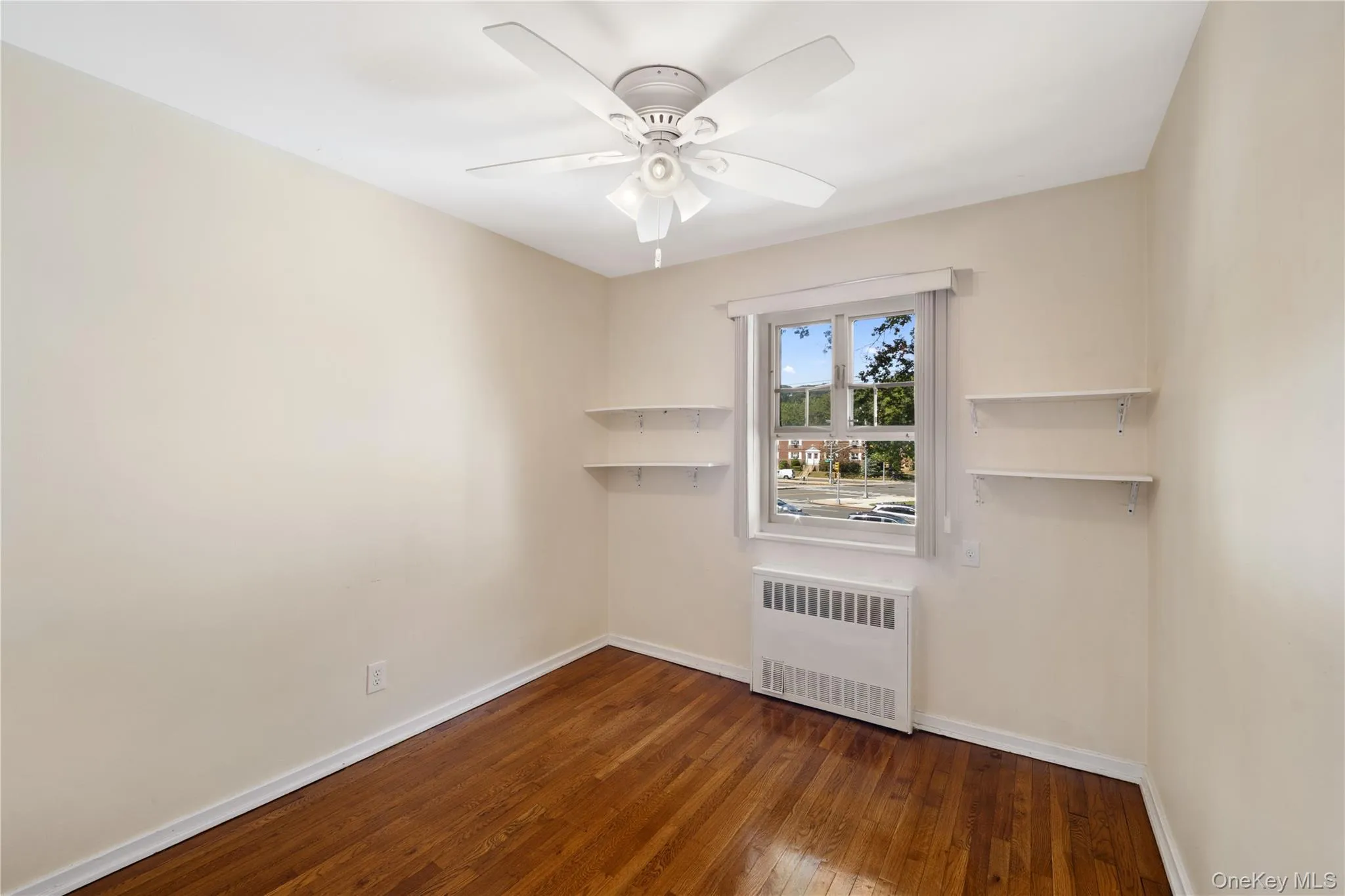 Spare room with radiator, dark wood finished floors, and a ceiling fan Spare room with radiator, dark wood finished floors, and a ceiling fan