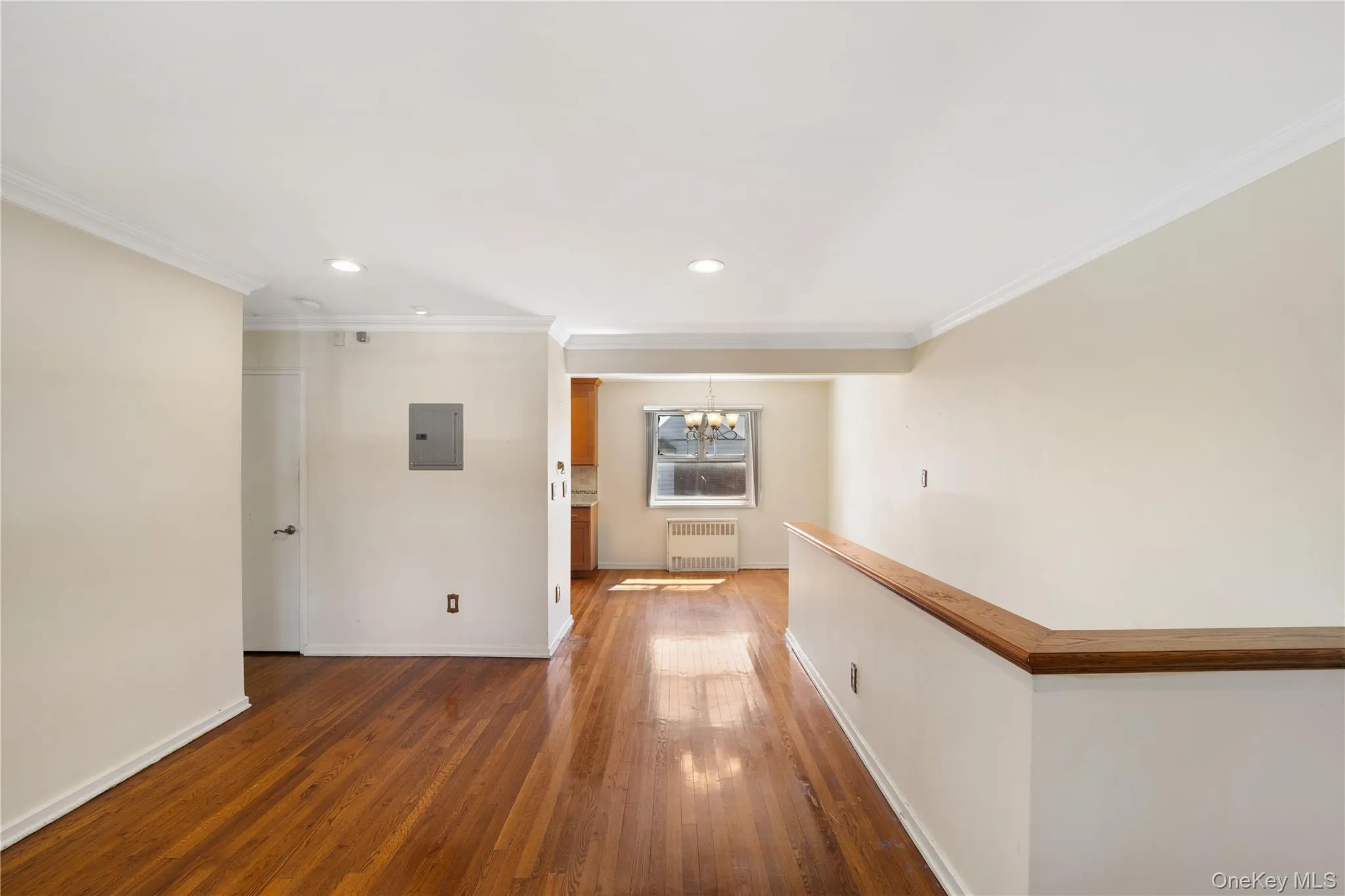 Hallway featuring crown molding, dark wood-style flooring, a chandelier, electric panel, and radiator heating unit Hallway featuring crown molding, dark wood-style flooring, a chandelier, electric panel, and radiator heating unit
