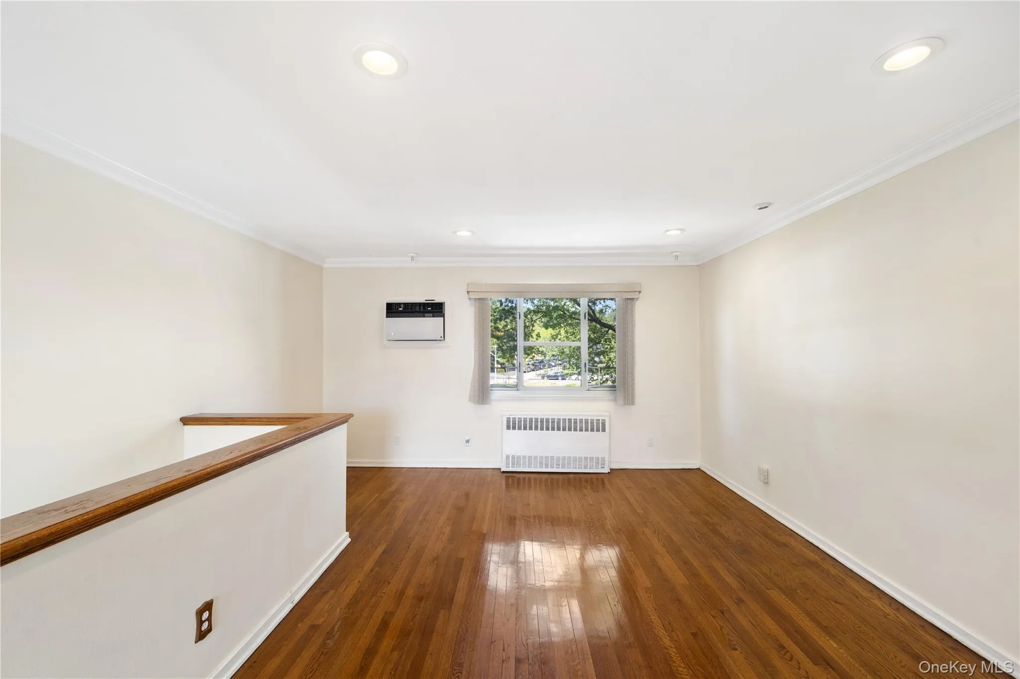 Empty room with ornamental molding, radiator, dark wood-type flooring, and recessed lighting Empty room with ornamental molding, radiator, dark wood-type flooring, and recessed lighting
