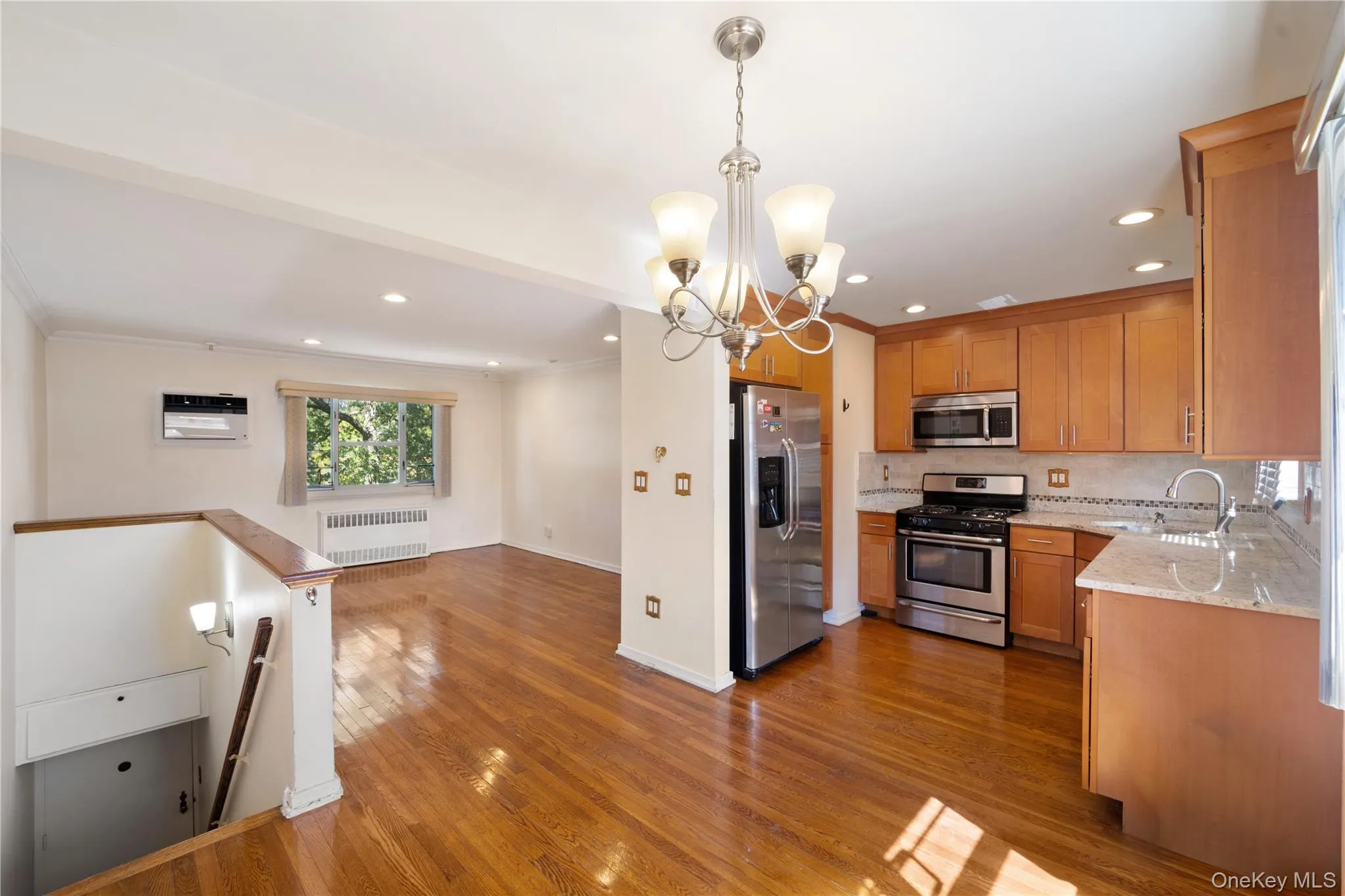Kitchen featuring light stone counters, stainless steel appliances, open floor plan, a chandelier, and crown molding Kitchen featuring light stone counters, stainless steel appliances, open floor plan, a chandelier, and crown molding