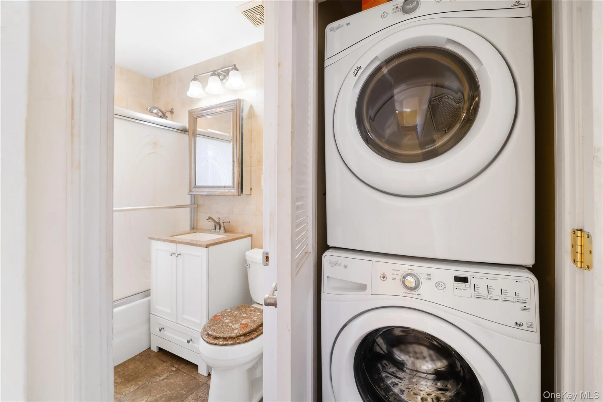 Washroom featuring stacked washer and clothes dryer and a sink Washroom featuring stacked washer and clothes dryer and a sink