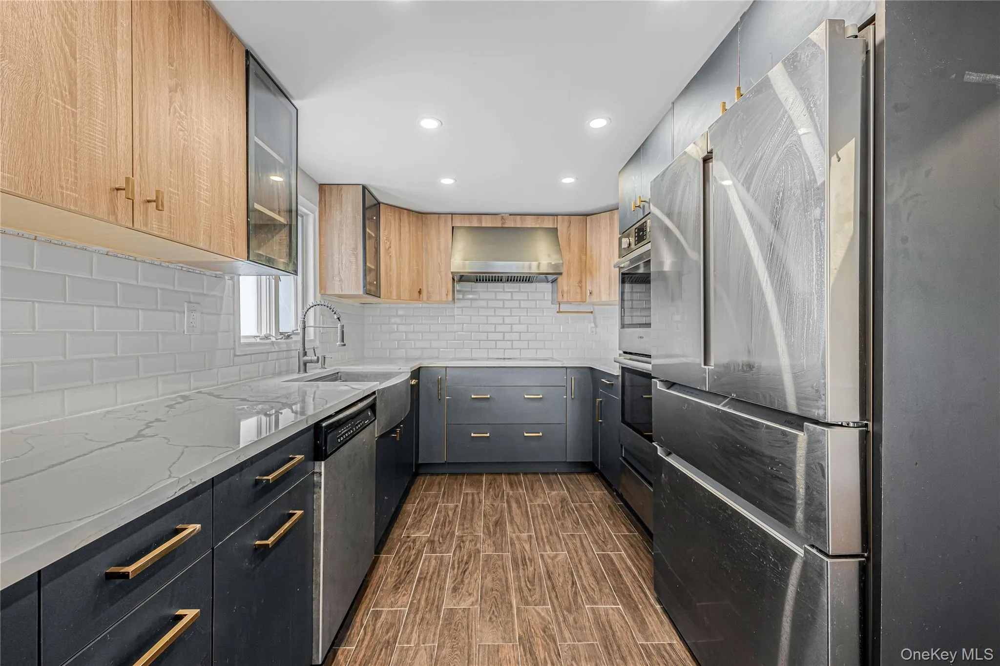 Kitchen featuring decorative backsplash, stainless steel appliances, light stone countertops, glass insert cabinets, and dark wood-style floors Kitchen featuring decorative backsplash, stainless steel appliances, light stone countertops, glass insert cabinets, and dark wood-style floors