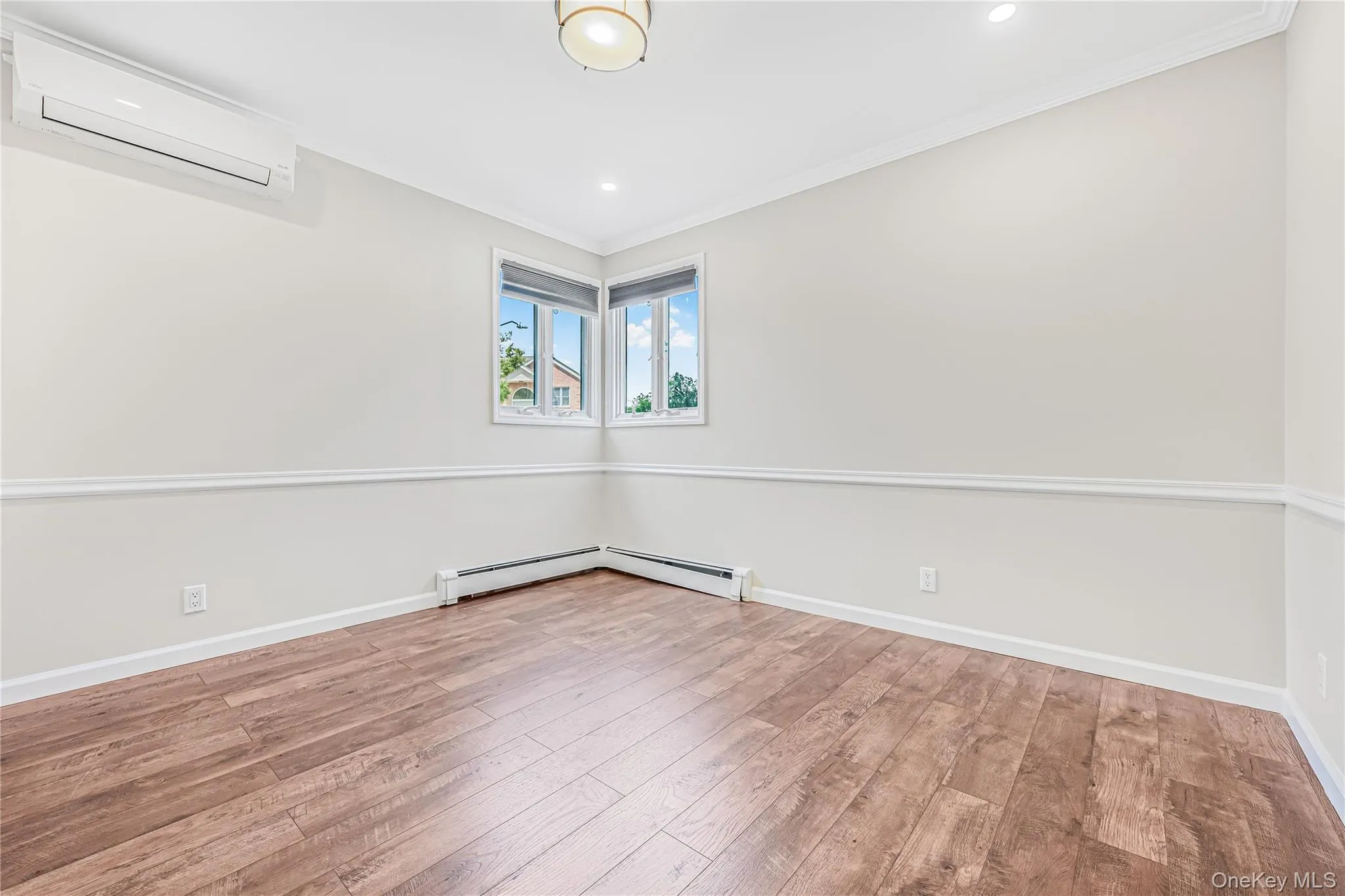 Empty room featuring a wall mounted air conditioner, ornamental molding, light wood-style floors, recessed lighting, and a baseboard radiator Empty room featuring a wall mounted air conditioner, ornamental molding, light wood-style floors, recessed lighting, and a baseboard radiator