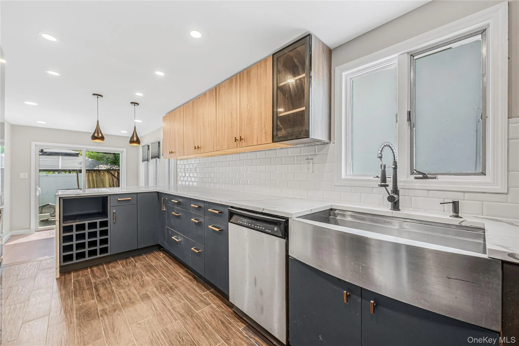 Kitchen with glass insert cabinets, stainless steel dishwasher, decorative light fixtures, decorative backsplash, and recessed lighting Kitchen with glass insert cabinets, stainless steel dishwasher, decorative light fixtures, decorative backsplash, and recessed lighting
