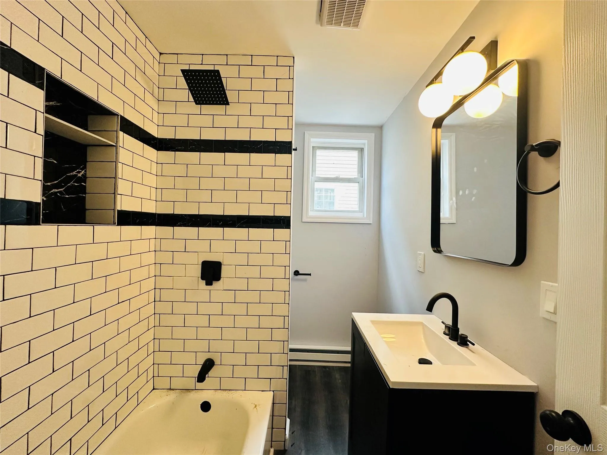 Bathroom with bathtub / shower combination, vanity, and a baseboard radiator Bathroom with bathtub / shower combination, vanity, and a baseboard radiator