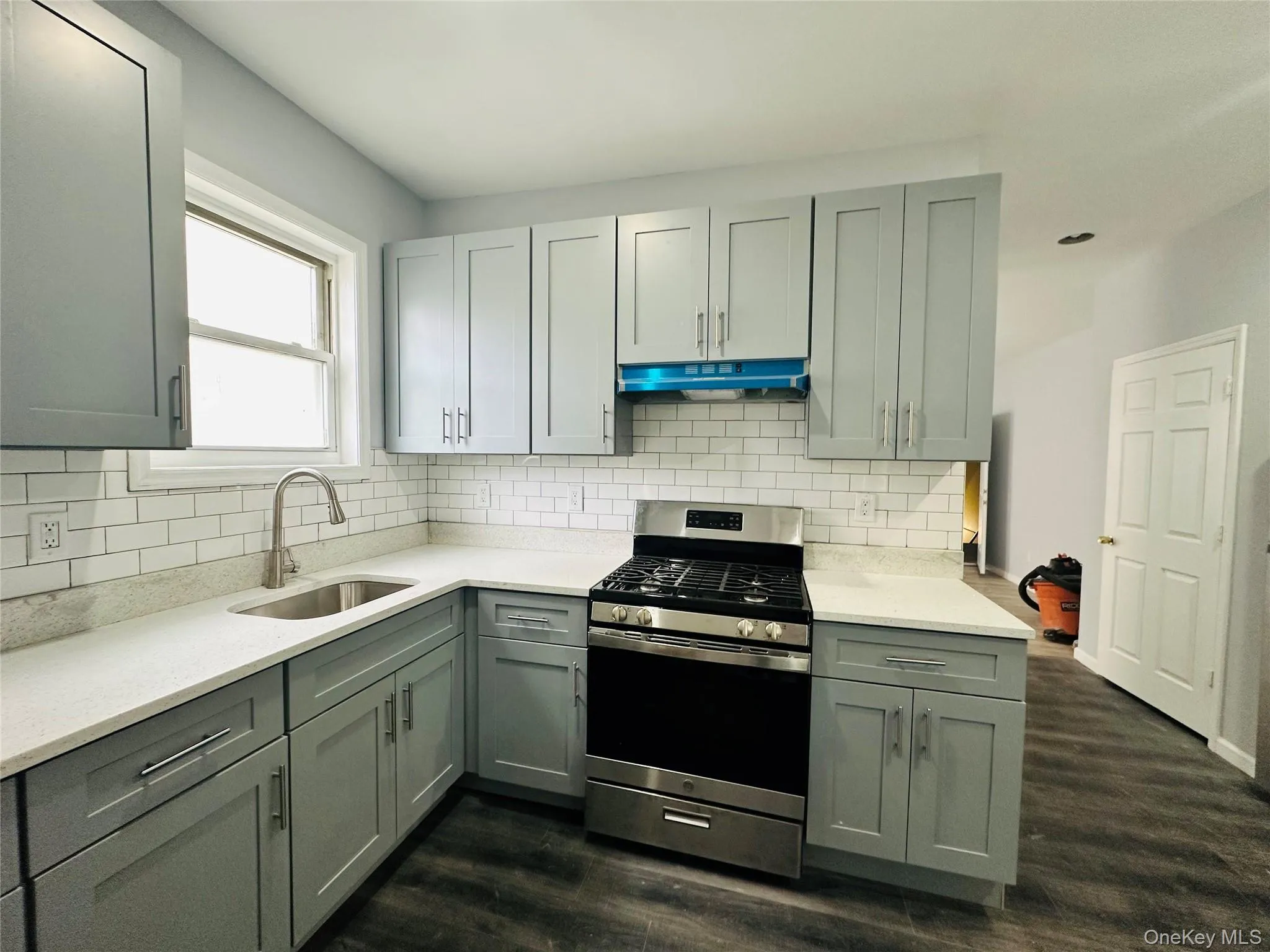 Kitchen featuring gas range, light stone countertops, gray cabinets, and dark wood-style flooring Kitchen featuring gas range, light stone countertops, gray cabinets, and dark wood-style flooring