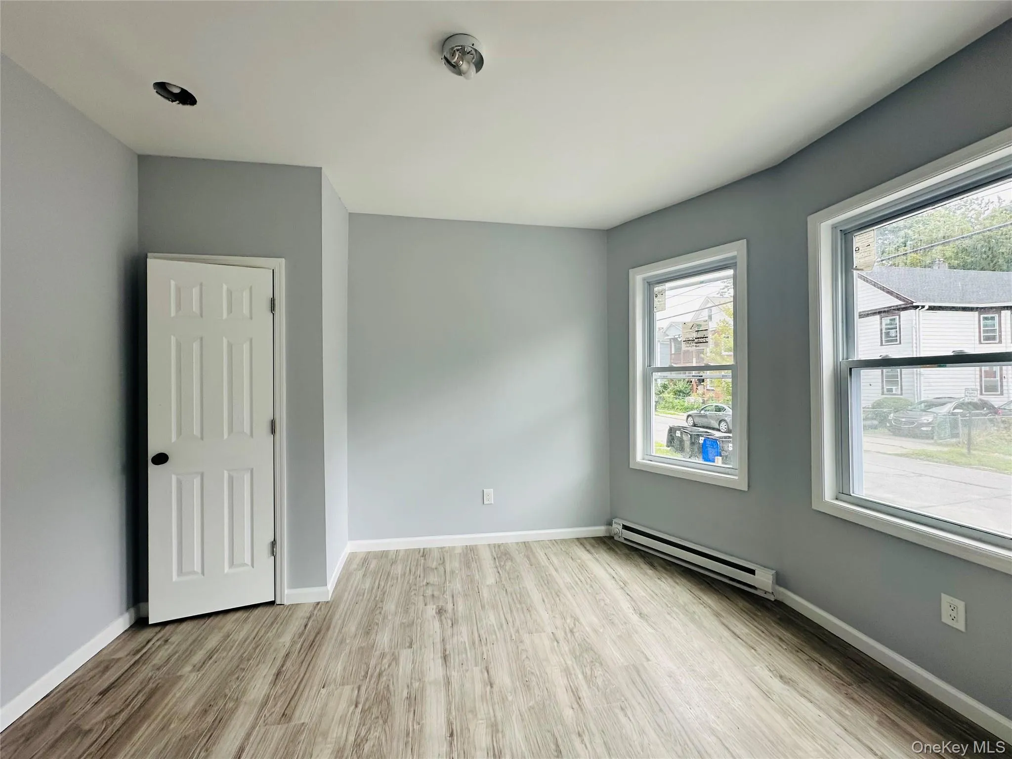 Empty room with light wood-style flooring and baseboard heating Empty room with light wood-style flooring and baseboard heating