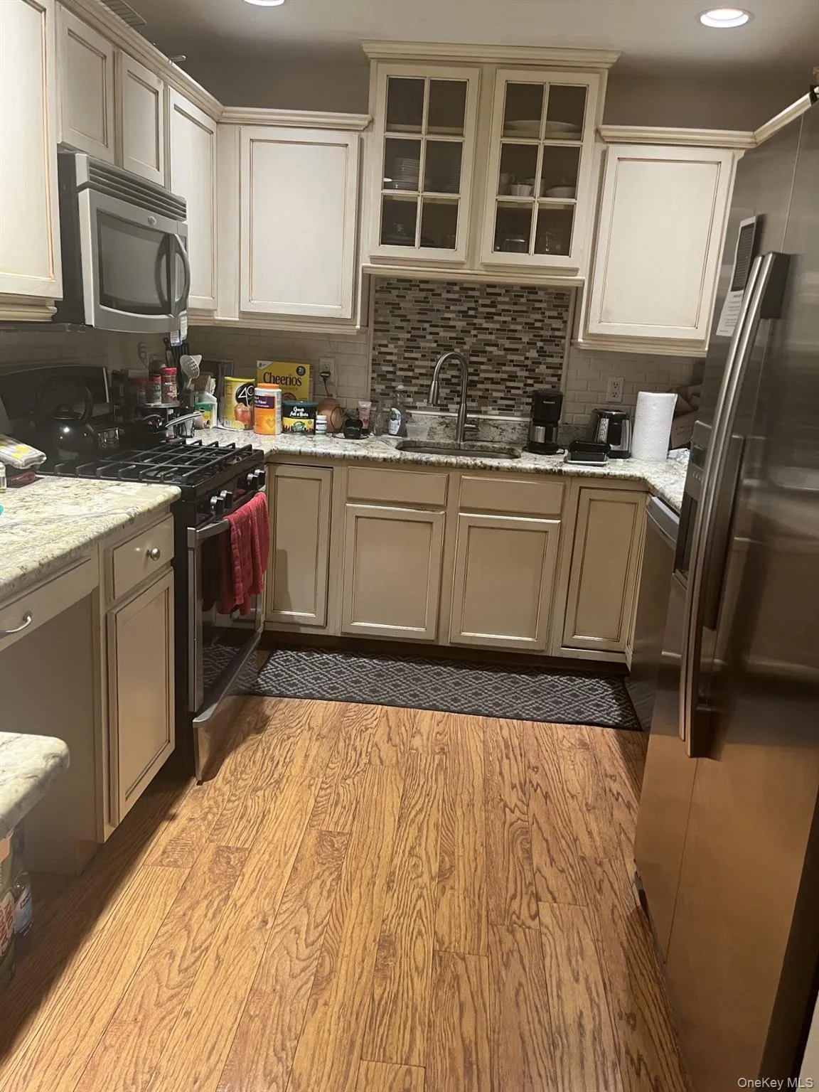 Kitchen featuring stainless steel appliances, tasteful backsplash, light wood-style flooring, light stone countertops, and recessed lighting Kitchen featuring stainless steel appliances, tasteful backsplash, light wood-style flooring, light stone countertops, and recessed lighting