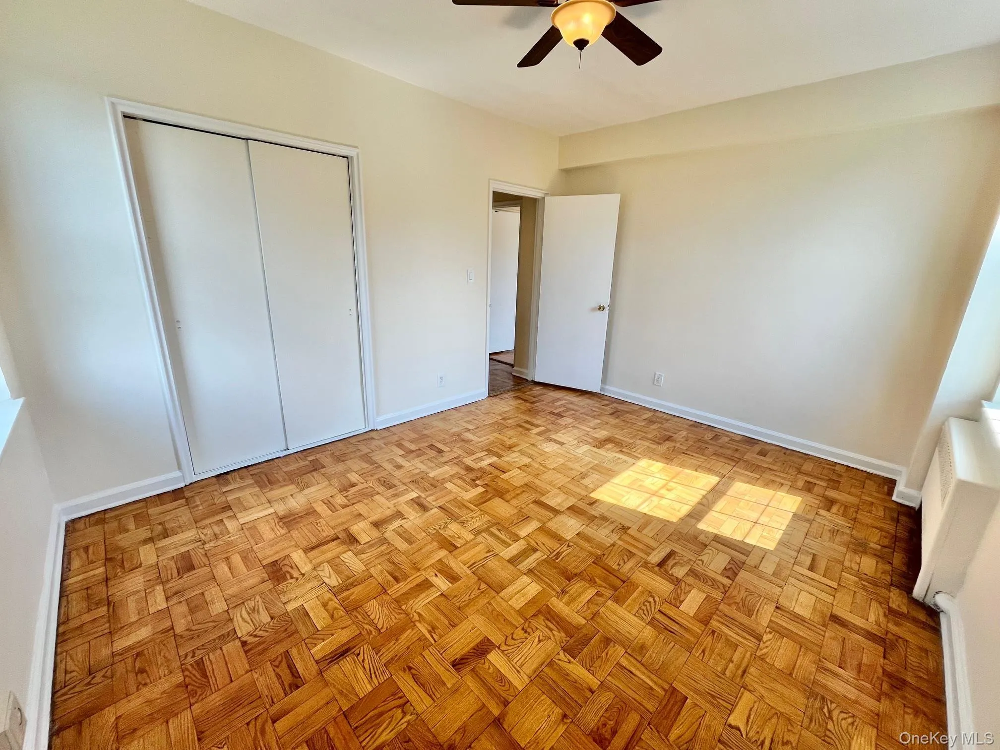 Unfurnished bedroom with a closet, ceiling fan, and baseboard heating Unfurnished bedroom with a closet, ceiling fan, and baseboard heating