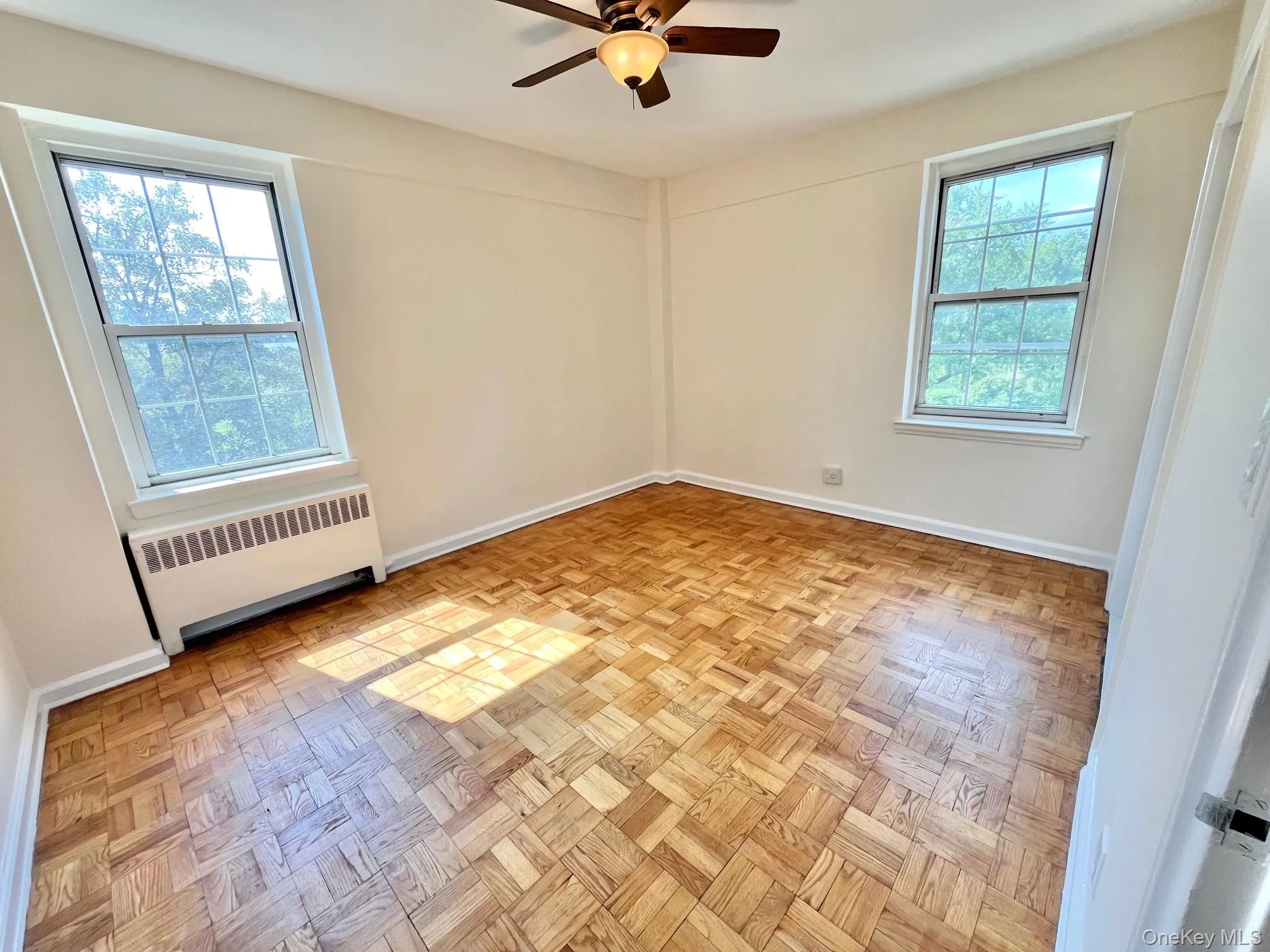 Empty room featuring radiator heating unit and ceiling fan Empty room featuring radiator heating unit and ceiling fan