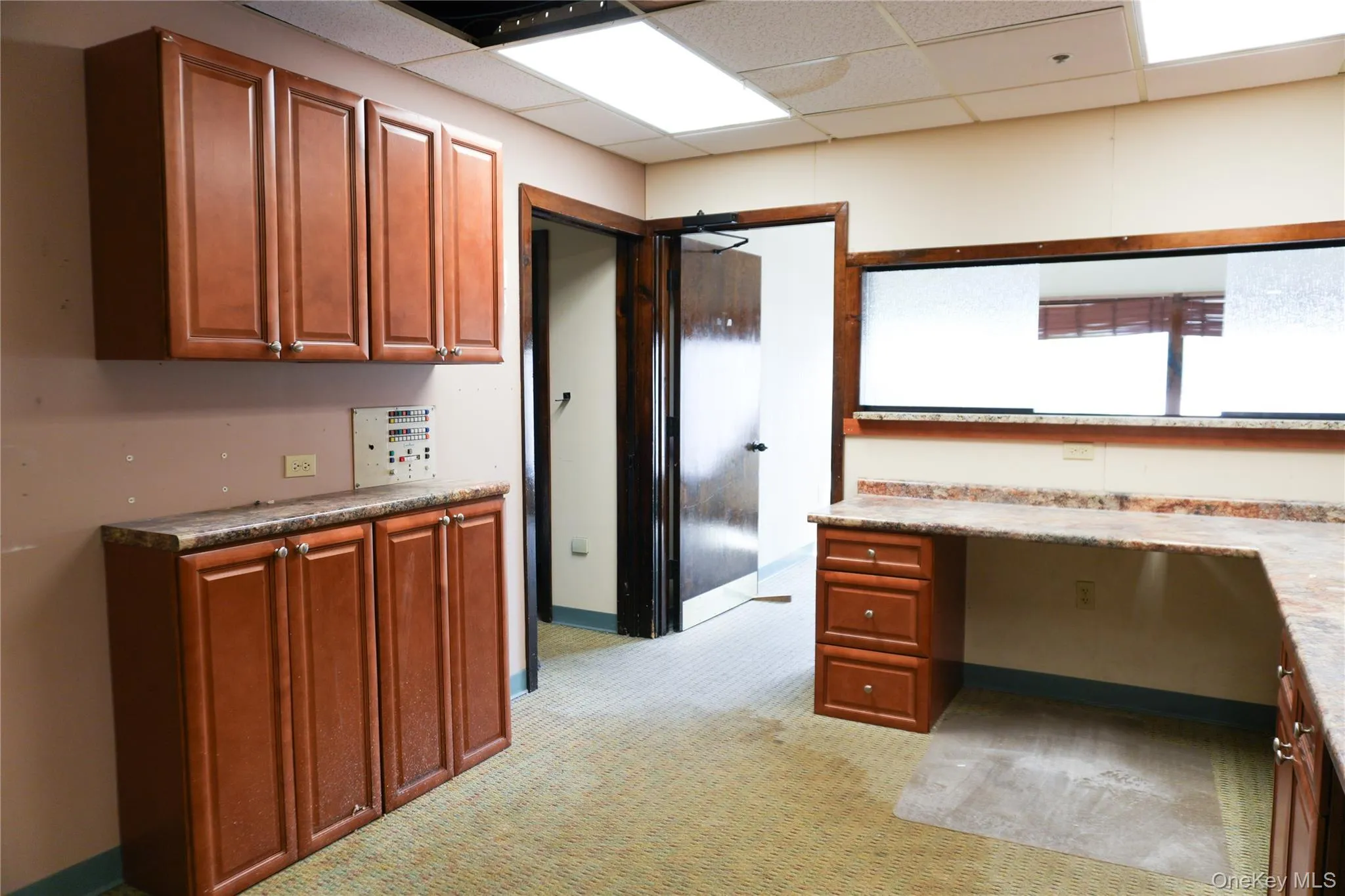 Kitchen with a paneled ceiling, light colored carpet, brown cabinetry, and built in study area Kitchen with a paneled ceiling, light colored carpet, brown cabinetry, and built in study area