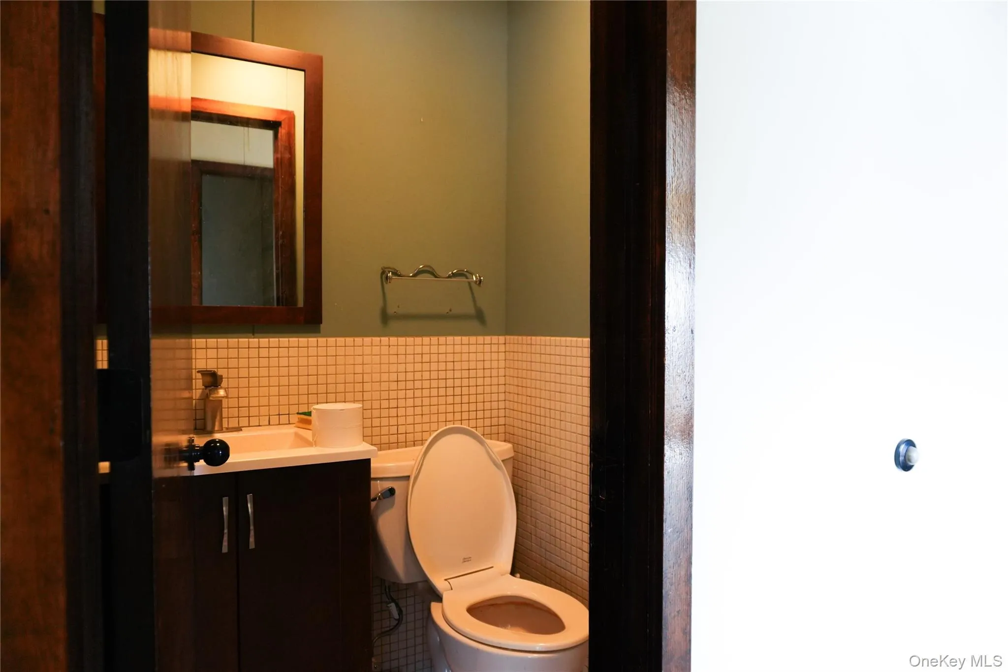 Bathroom featuring tile walls, vanity, and wainscoting Bathroom featuring tile walls, vanity, and wainscoting