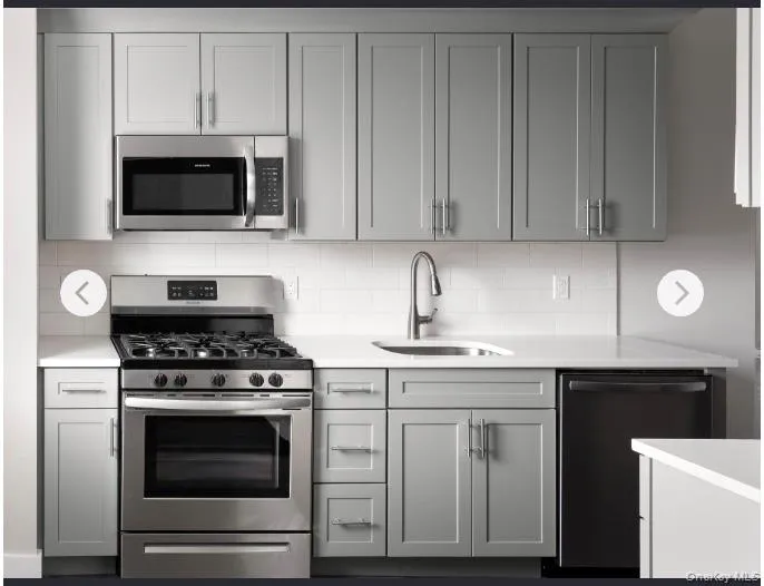 Kitchen featuring appliances with stainless steel finishes, gray cabinetry, tasteful backsplash, and light stone countertops Kitchen featuring appliances with stainless steel finishes, gray cabinetry, tasteful backsplash, and light stone countertops