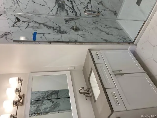 Bathroom featuring a marble finish shower and vanity Bathroom featuring a marble finish shower and vanity