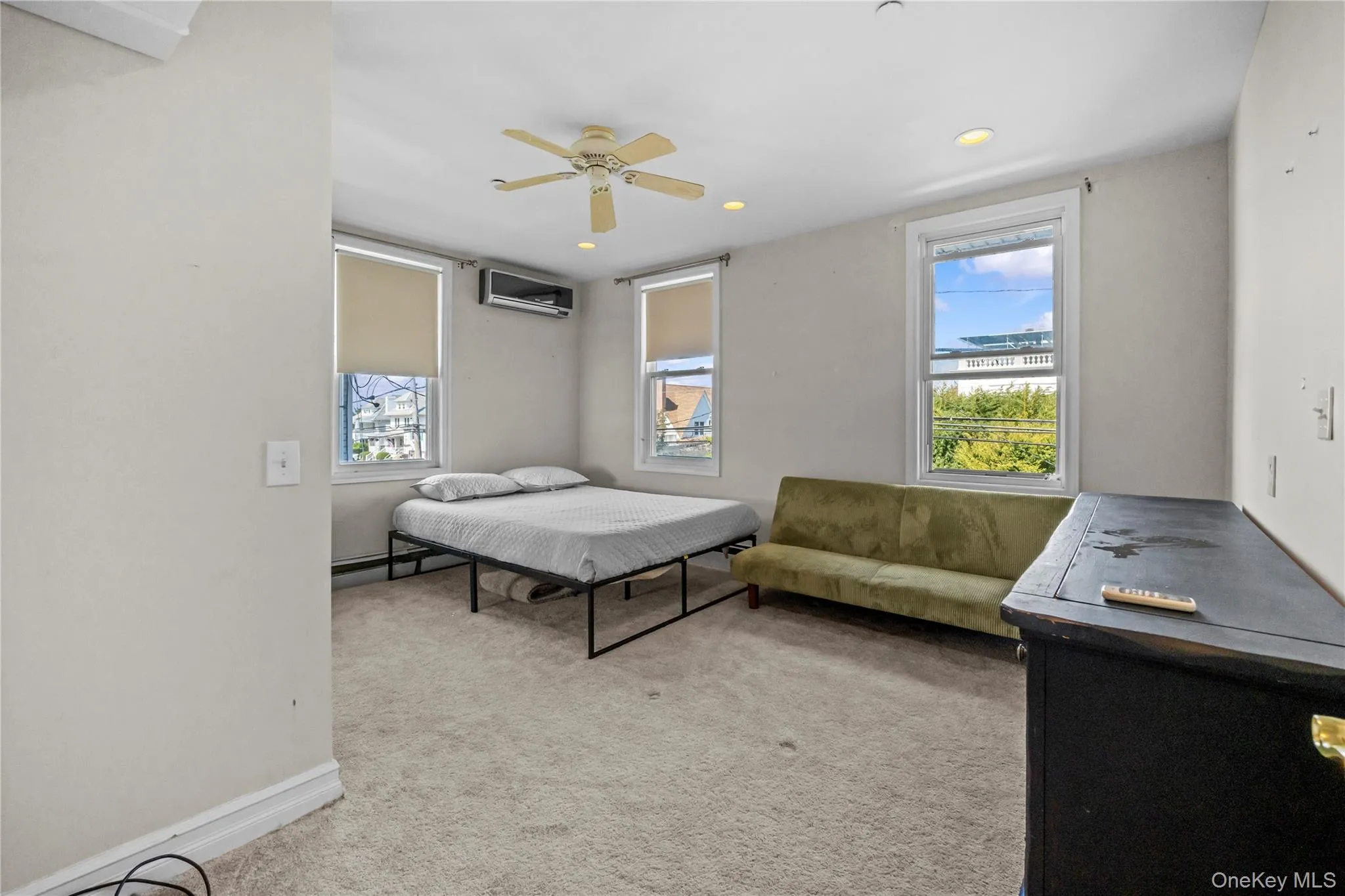 Bedroom with light colored carpet, a ceiling fan, recessed lighting, a baseboard heating unit, and an AC wall unit Bedroom with light colored carpet, a ceiling fan, recessed lighting, a baseboard heating unit, and an AC wall unit
