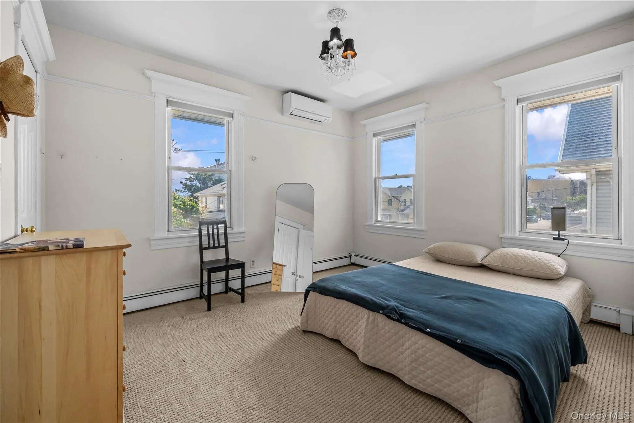 Bedroom featuring light carpet, a baseboard heating unit, and a wall mounted air conditioner Bedroom featuring light carpet, a baseboard heating unit, and a wall mounted air conditioner