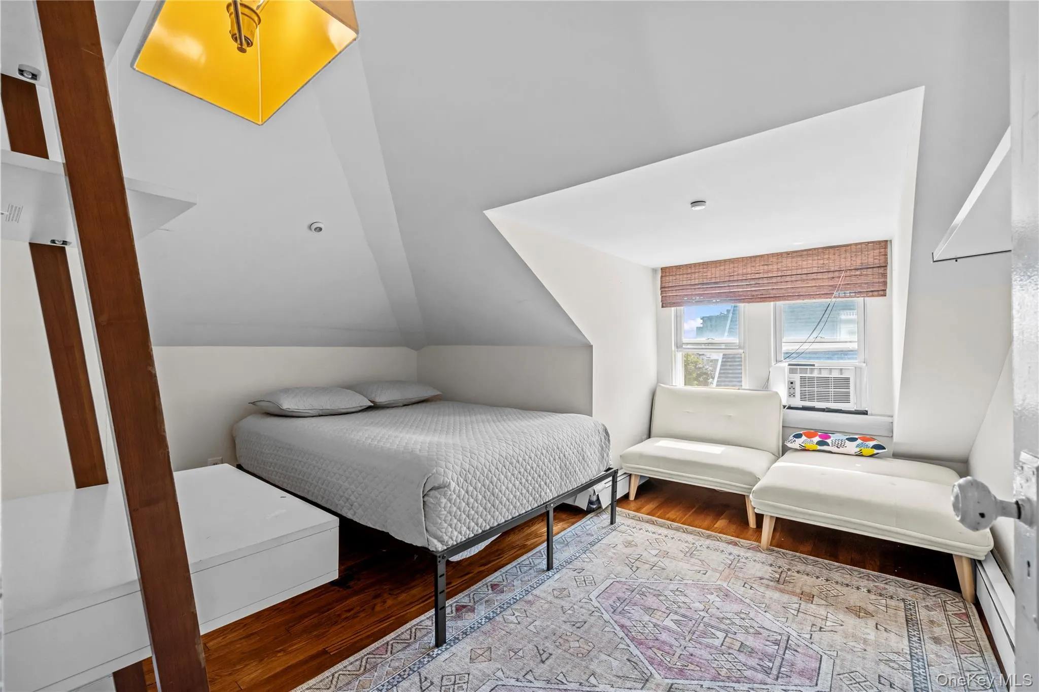Bedroom with wood finished floors, vaulted ceiling, and a baseboard radiator Bedroom with wood finished floors, vaulted ceiling, and a baseboard radiator