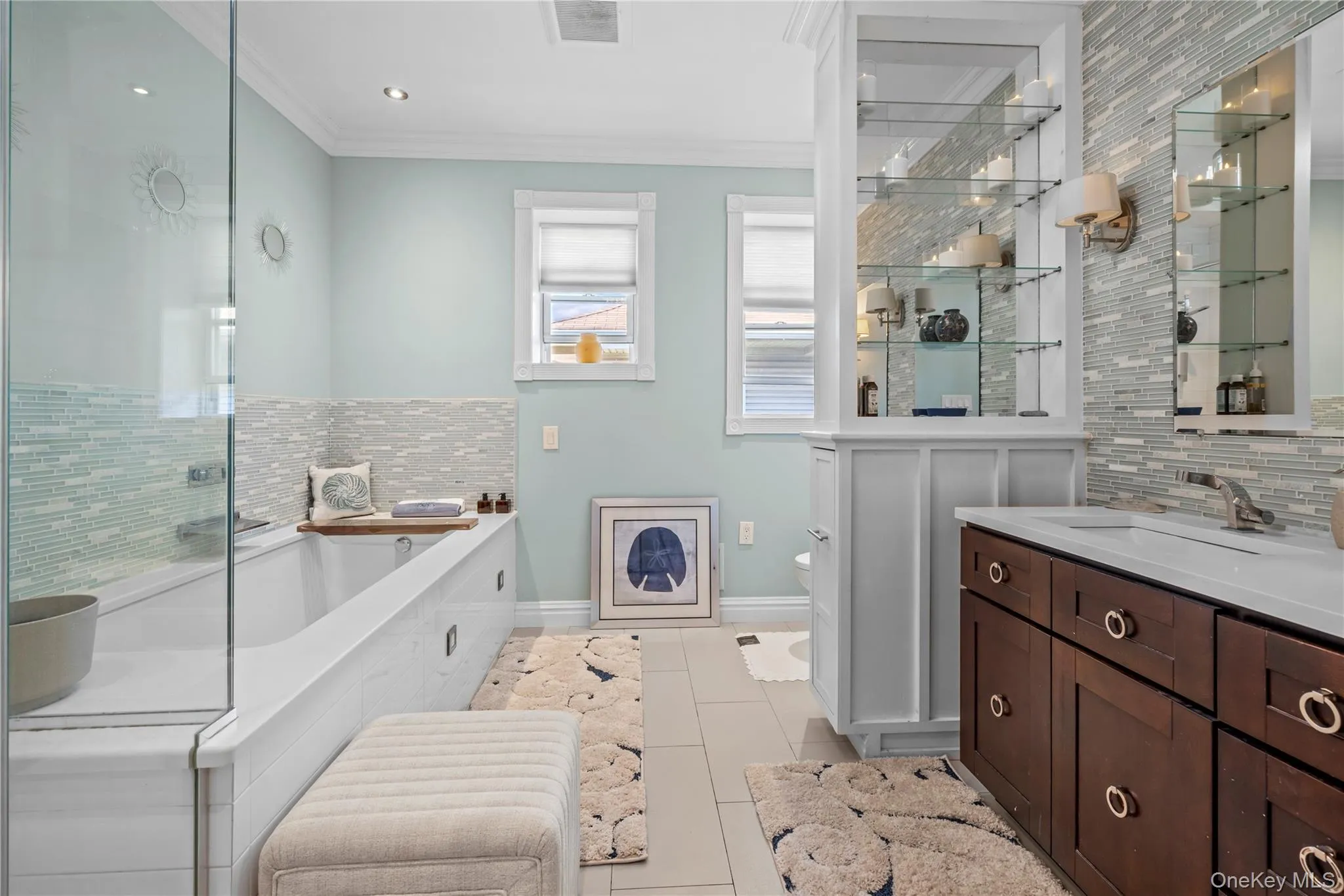 Bathroom featuring tasteful backsplash, a bath, crown molding, vanity, and light tile patterned floors Bathroom featuring tasteful backsplash, a bath, crown molding, vanity, and light tile patterned floors