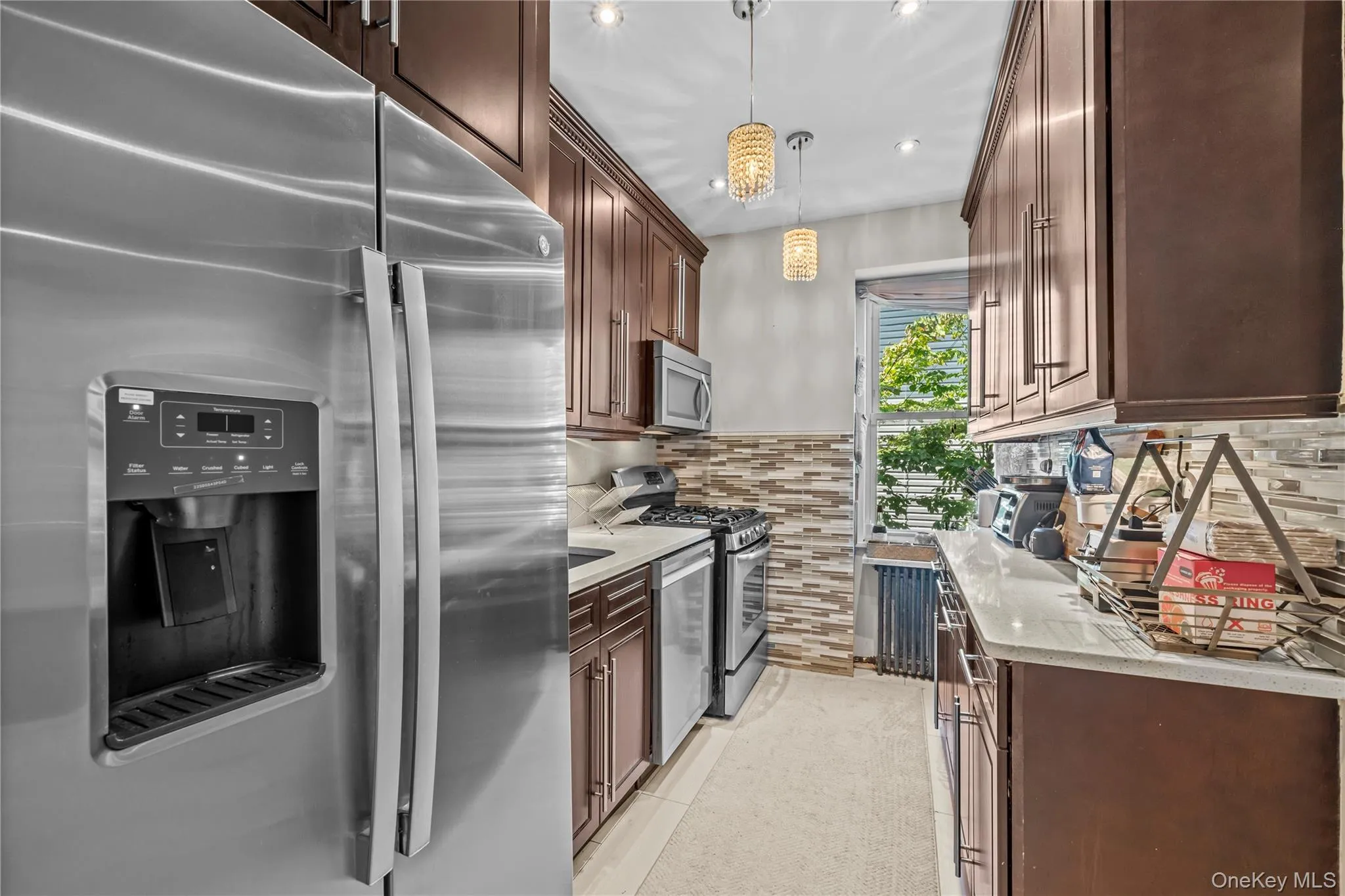 Kitchen with stainless steel appliances, light stone counters, tasteful backsplash, and dark brown cabinetry Kitchen with stainless steel appliances, light stone counters, tasteful backsplash, and dark brown cabinetry