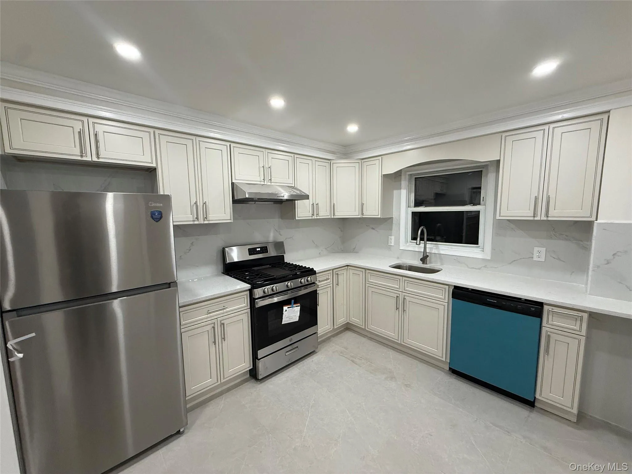 Kitchen featuring backsplash, stainless steel appliances, recessed lighting, under cabinet range hood, and light stone counters Kitchen featuring backsplash, stainless steel appliances, recessed lighting, under cabinet range hood, and light stone counters