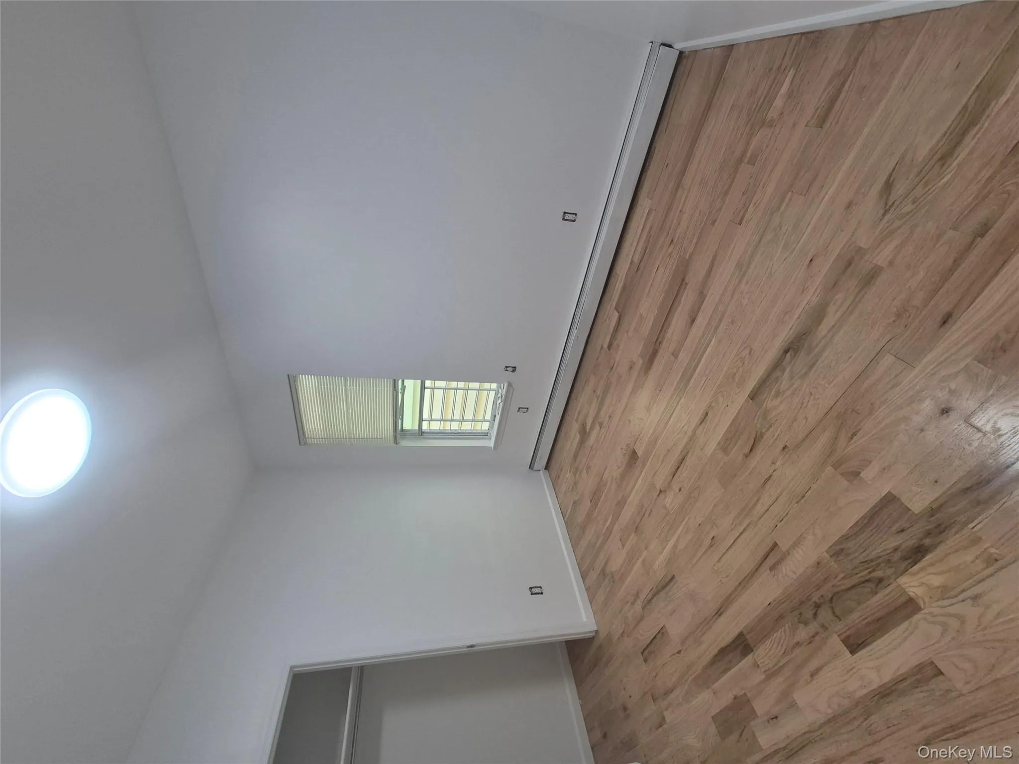 Unfurnished bedroom featuring a baseboard heating unit, light wood finished floors, and a closet Unfurnished bedroom featuring a baseboard heating unit, light wood finished floors, and a closet