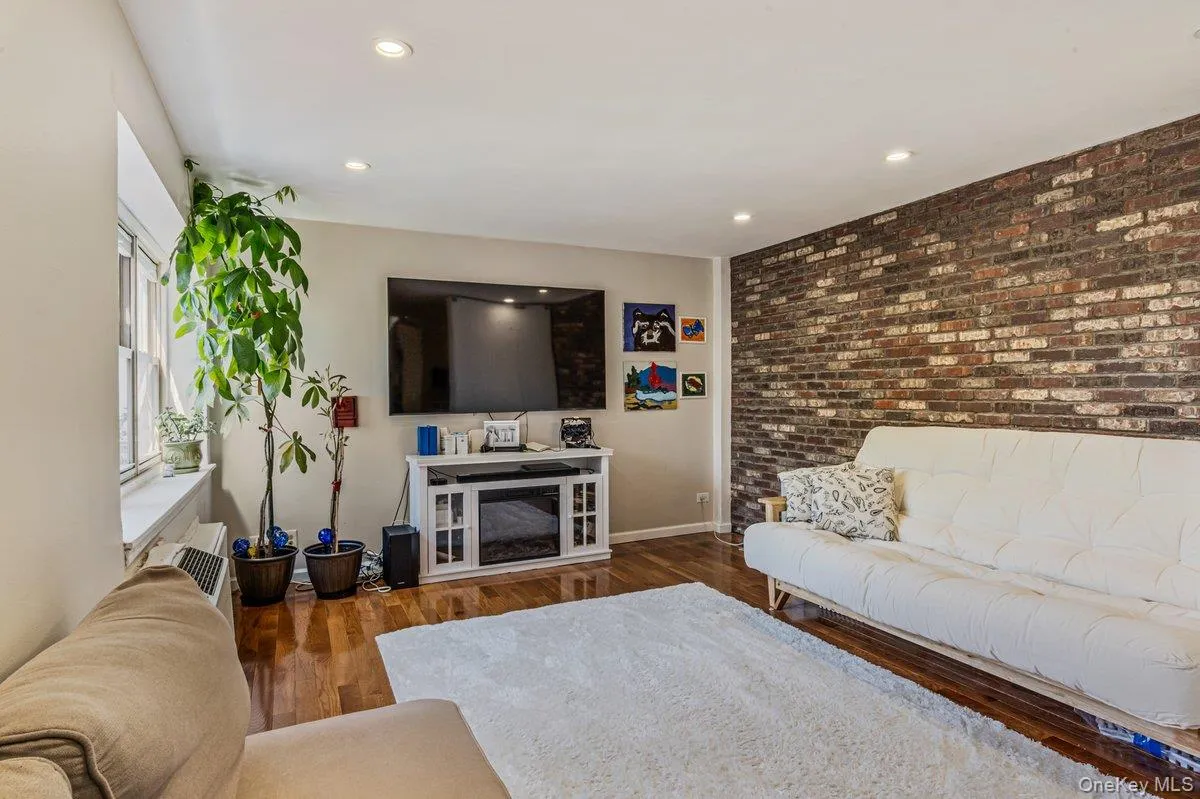 Living room with brick wall, dark wood-type flooring, and recessed lighting Living room with brick wall, dark wood-type flooring, and recessed lighting