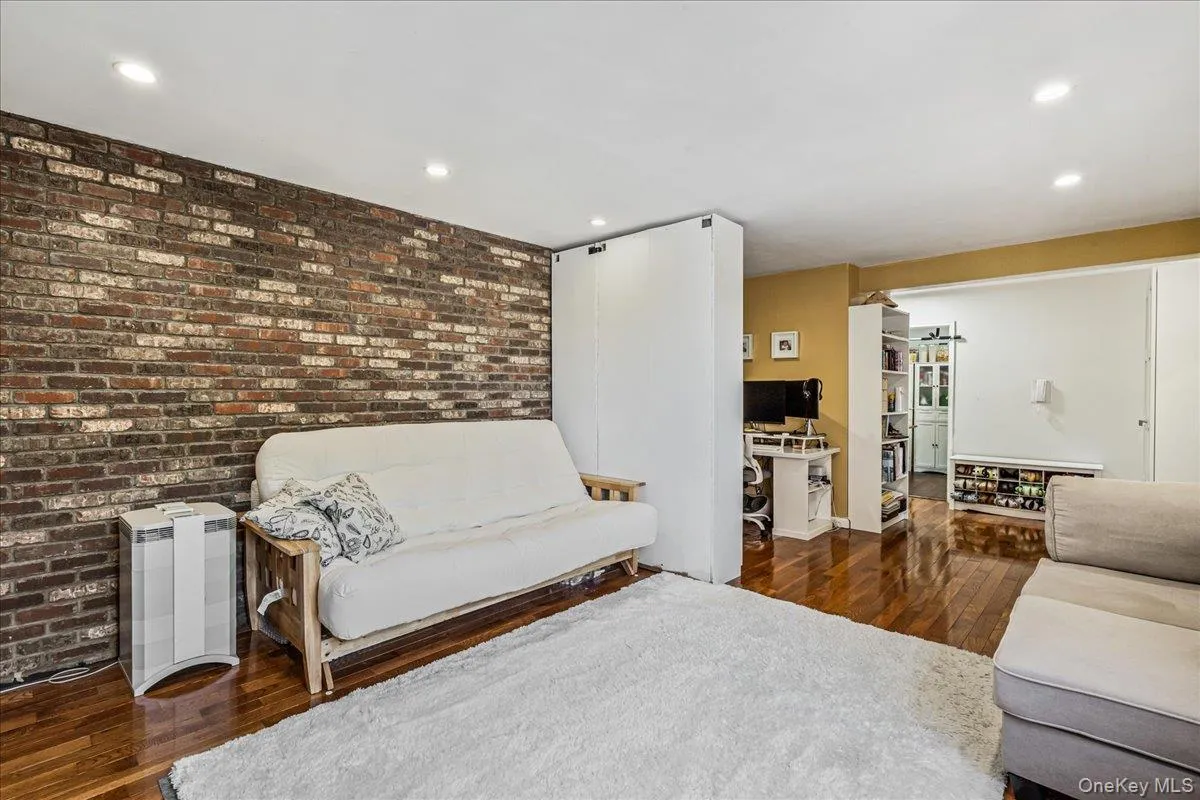 Living area featuring dark wood-style floors, brick wall, recessed lighting, and an office area Living area featuring dark wood-style floors, brick wall, recessed lighting, and an office area