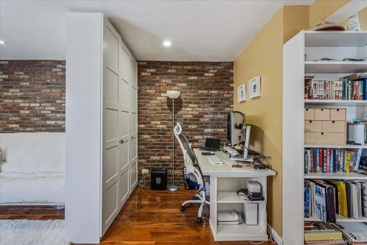 Home office featuring brick wall and dark wood finished floors Home office featuring brick wall and dark wood finished floors