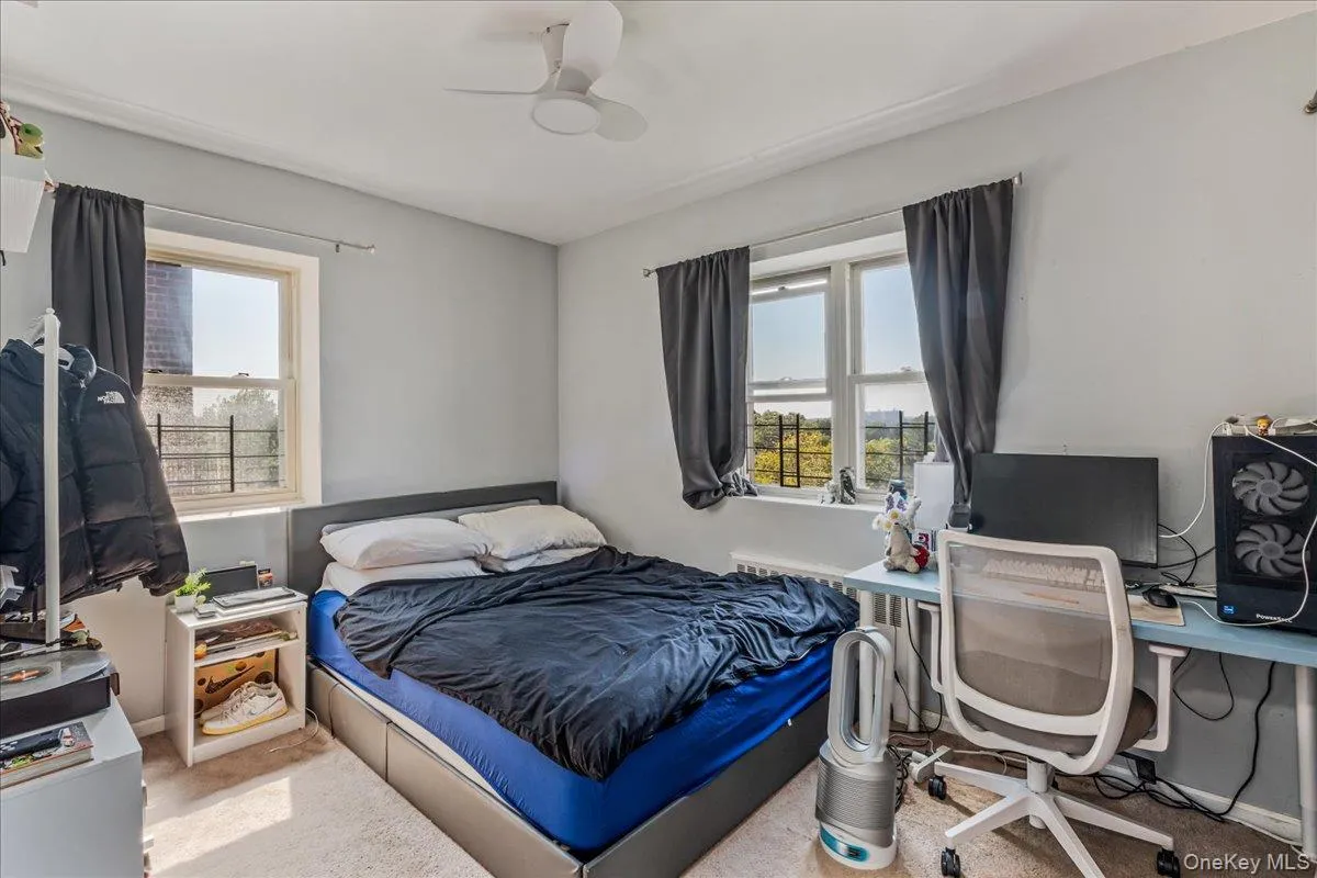 Carpeted bedroom featuring a desk and a ceiling fan Carpeted bedroom featuring a desk and a ceiling fan