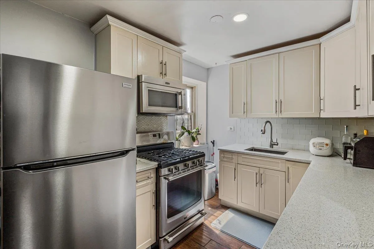 Kitchen with stainless steel appliances, light stone counters, decorative backsplash, dark wood-style floors, and recessed lighting Kitchen with stainless steel appliances, light stone counters, decorative backsplash, dark wood-style floors, and recessed lighting