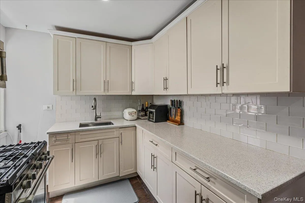 Kitchen featuring light stone countertops, gas stove, and backsplash Kitchen featuring light stone countertops, gas stove, and backsplash