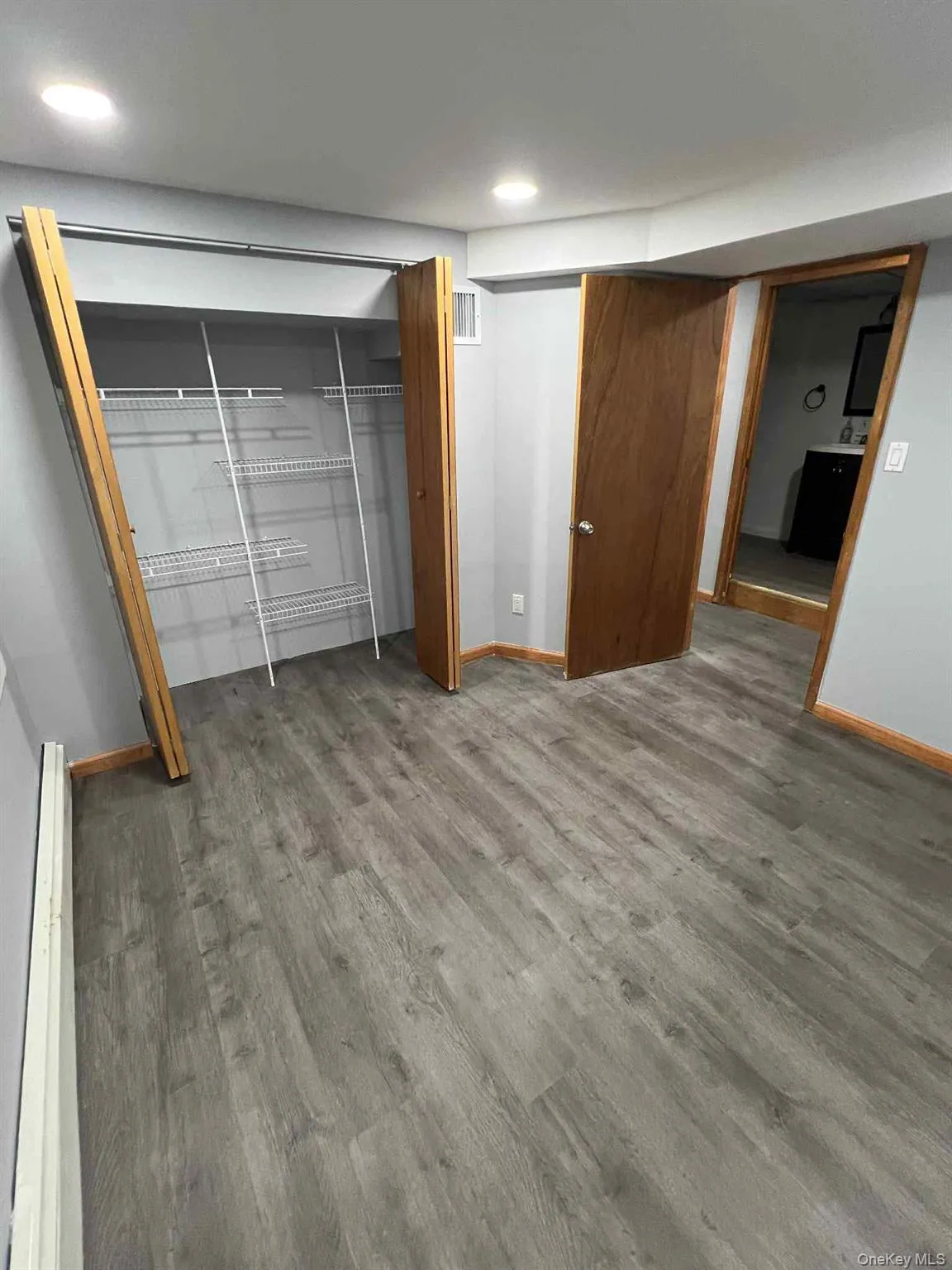 Unfurnished bedroom with wood finished floors, a closet, a baseboard heating unit, and recessed lighting Unfurnished bedroom with wood finished floors, a closet, a baseboard heating unit, and recessed lighting
