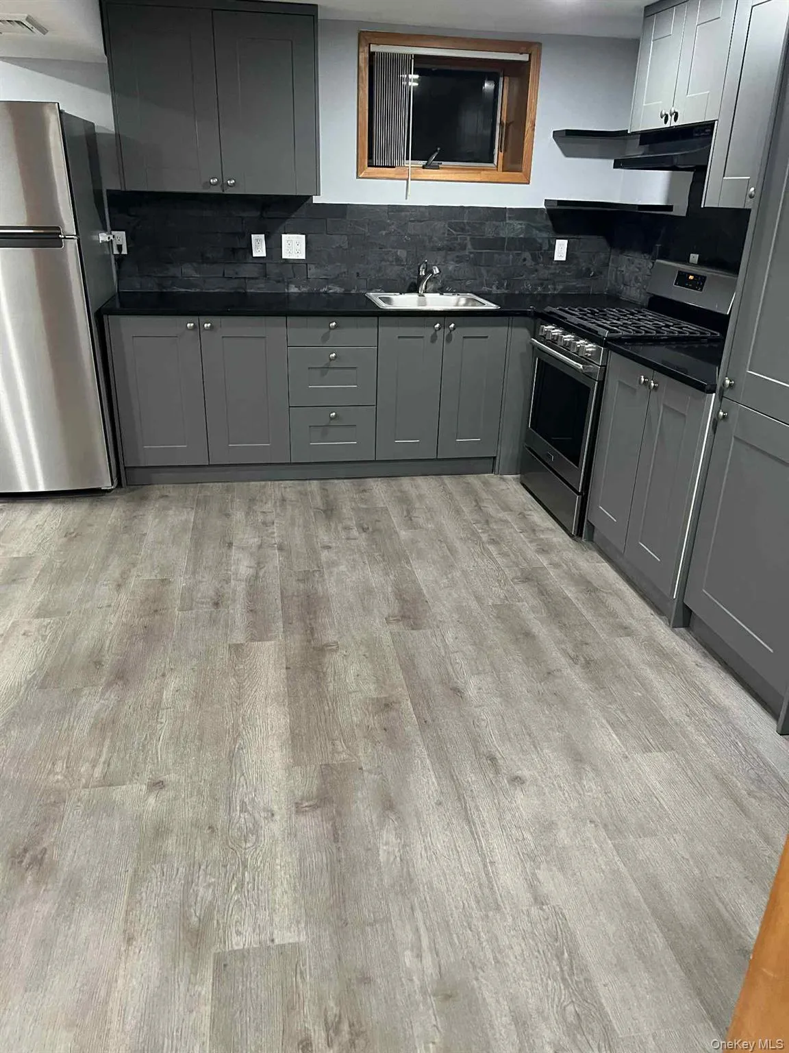 Kitchen featuring gray cabinetry, appliances with stainless steel finishes, open shelves, and backsplash Kitchen featuring gray cabinetry, appliances with stainless steel finishes, open shelves, and backsplash