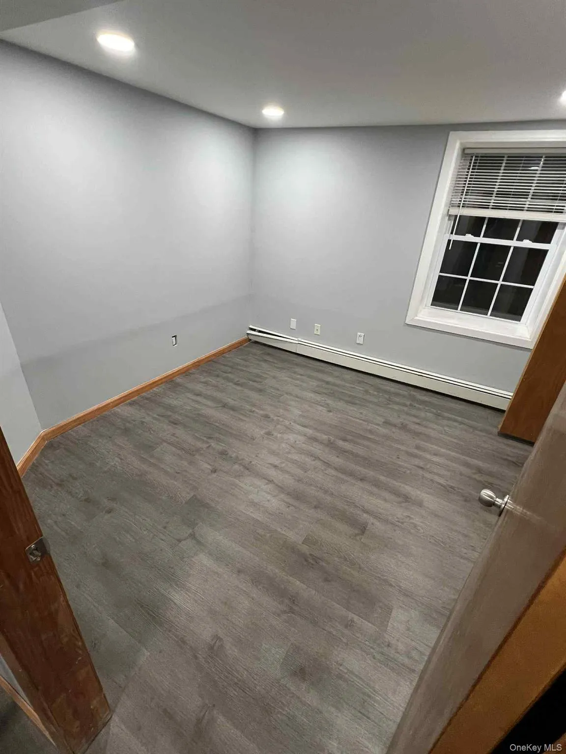 Unfurnished room featuring wood finished floors, a baseboard radiator, and recessed lighting Unfurnished room featuring wood finished floors, a baseboard radiator, and recessed lighting