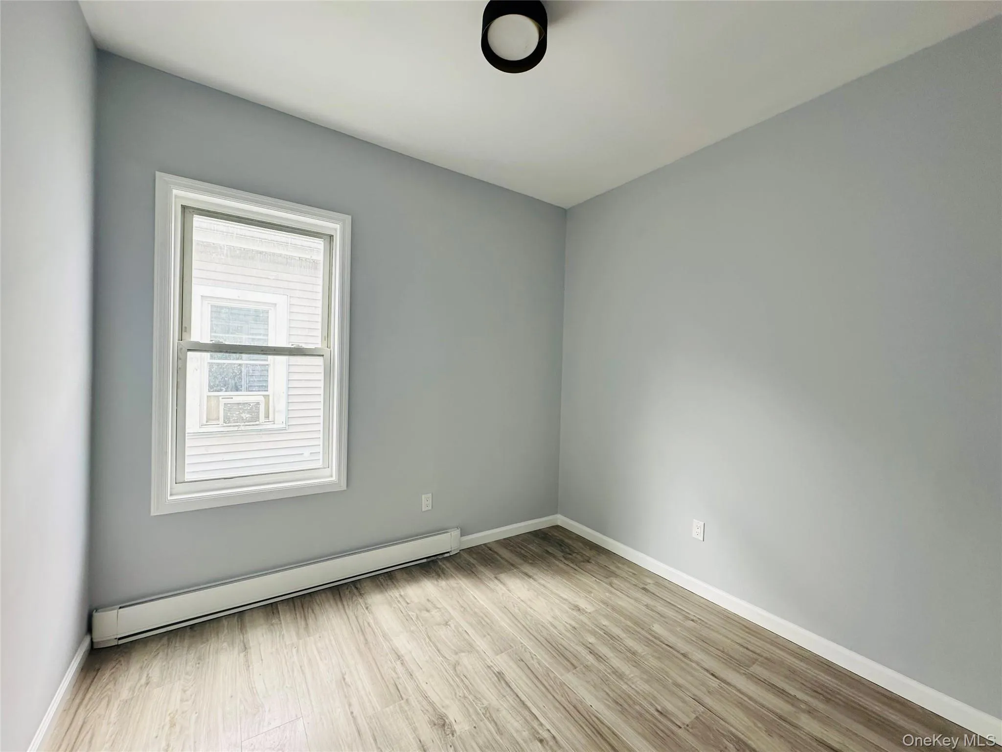 Empty room with a baseboard heating unit and light wood finished floors Empty room with a baseboard heating unit and light wood finished floors