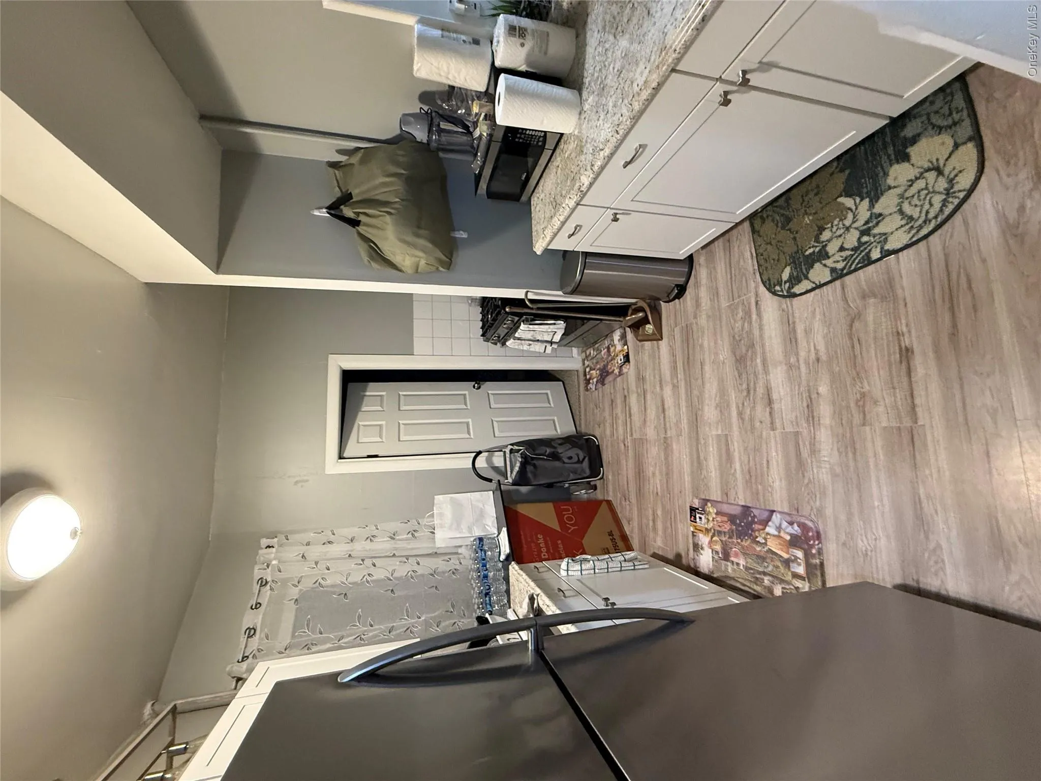 Kitchen featuring white cabinetry, stainless steel refrigerator, light wood finished floors, and light stone countertops Kitchen featuring white cabinetry, stainless steel refrigerator, light wood finished floors, and light stone countertops