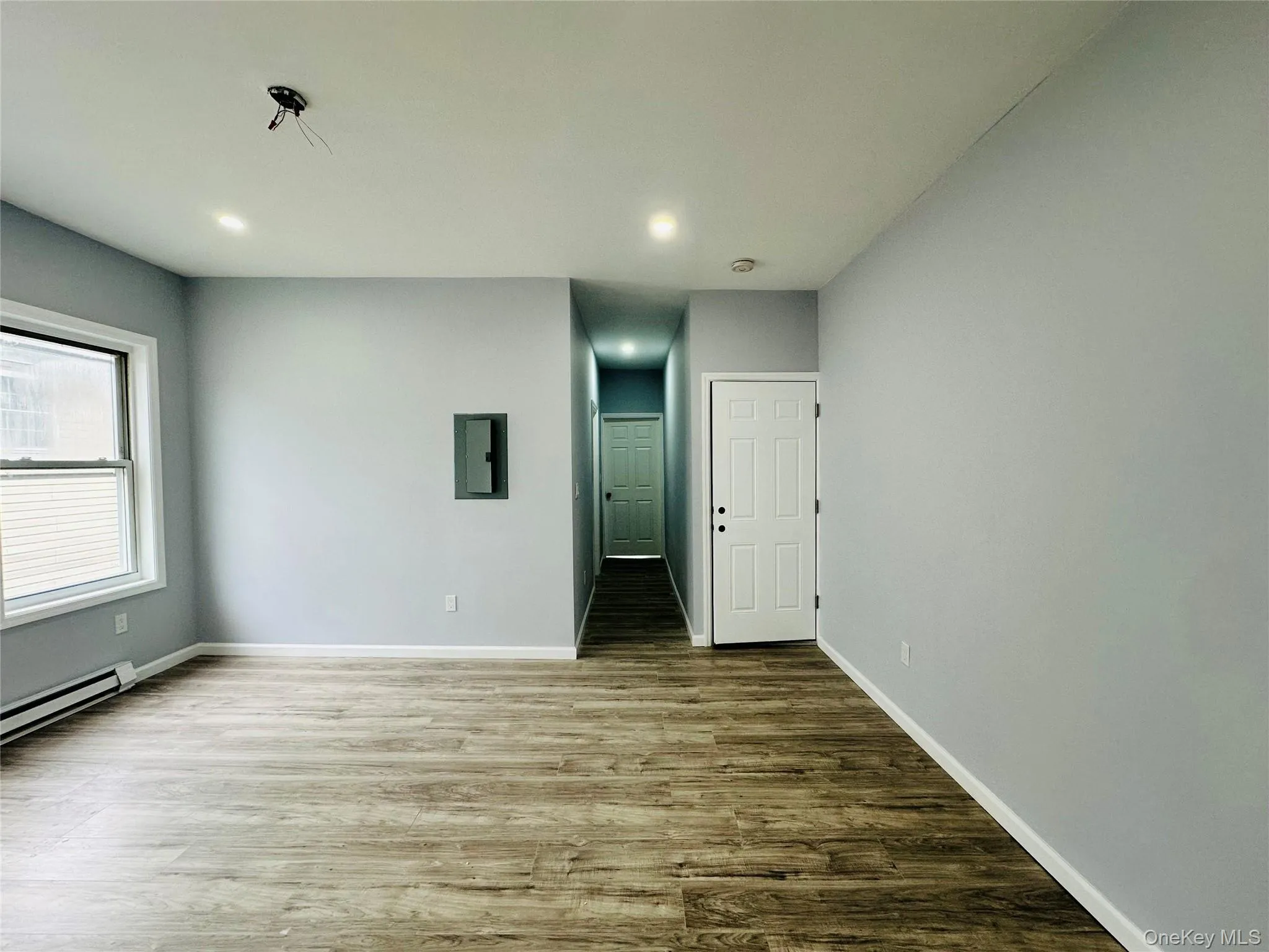 Empty room with wood finished floors, recessed lighting, and electric panel Empty room with wood finished floors, recessed lighting, and electric panel