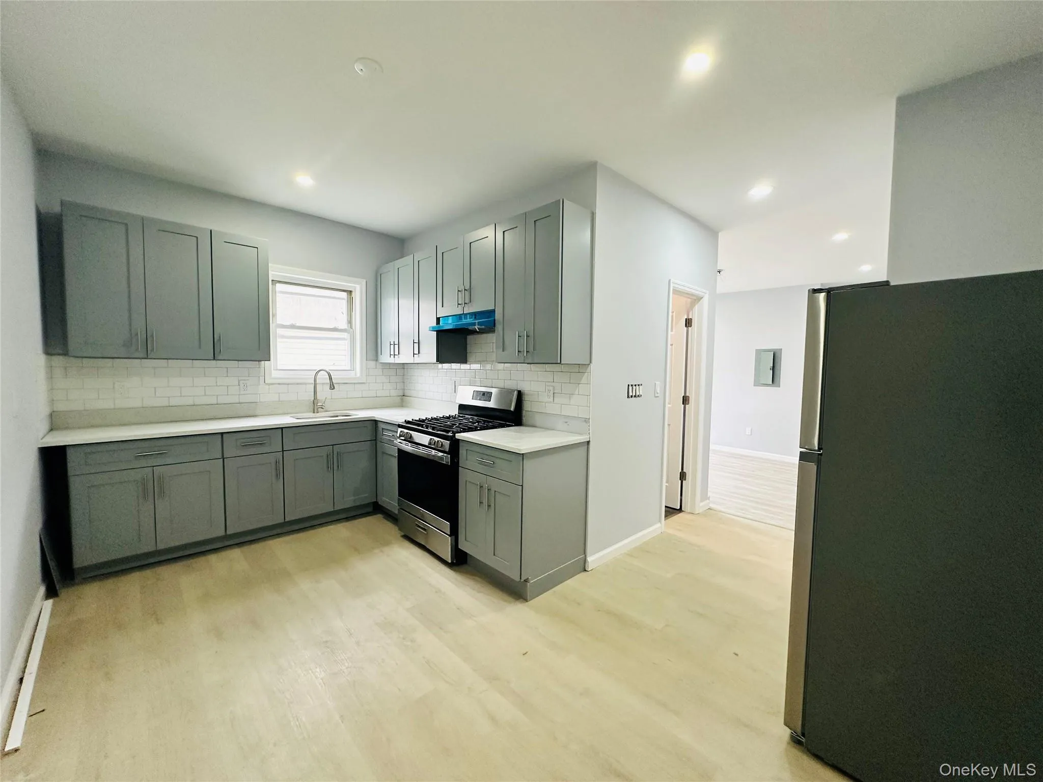 Kitchen featuring appliances with stainless steel finishes, light wood finished floors, tasteful backsplash, recessed lighting, and under cabinet range hood Kitchen featuring appliances with stainless steel finishes, light wood finished floors, tasteful backsplash, recessed lighting, and under cabinet range hood