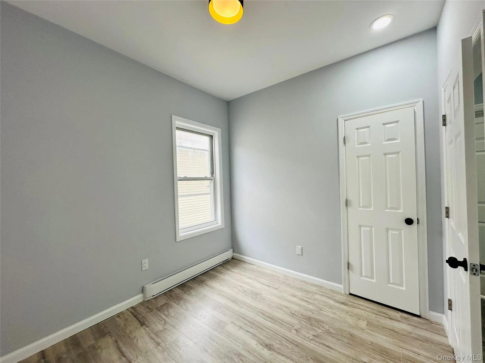 Unfurnished room featuring a baseboard heating unit and light wood-type flooring Unfurnished room featuring a baseboard heating unit and light wood-type flooring
