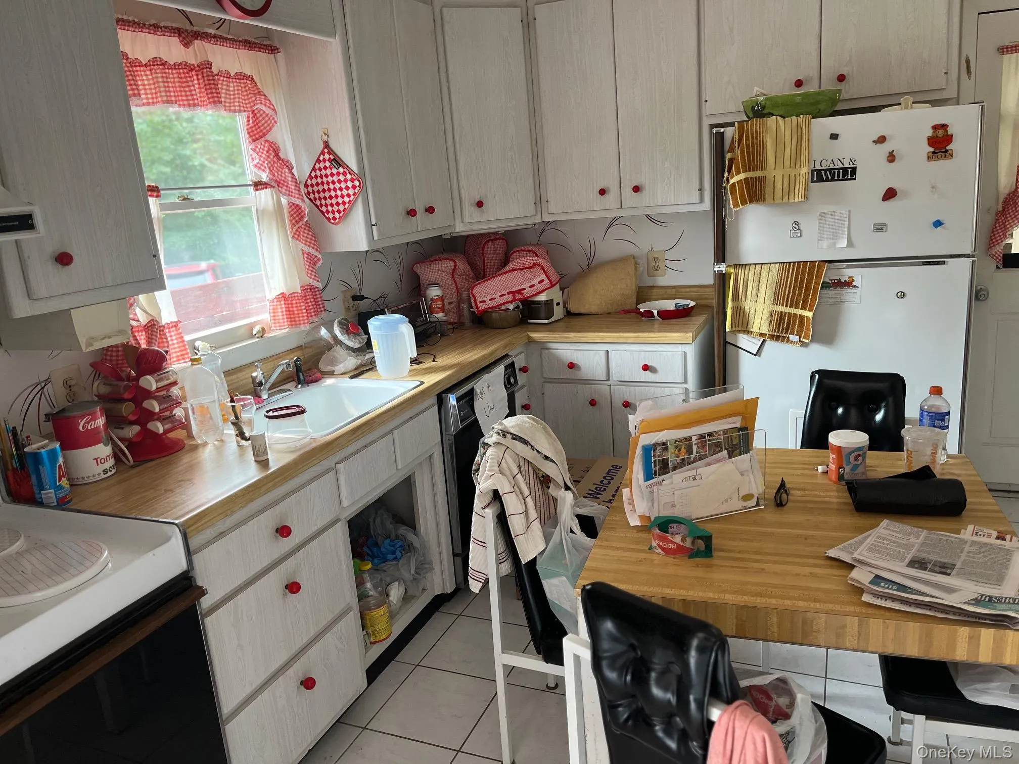 Kitchen featuring light countertops, freestanding refrigerator, light tile patterned floors, and electric range Kitchen featuring light countertops, freestanding refrigerator, light tile patterned floors, and electric range