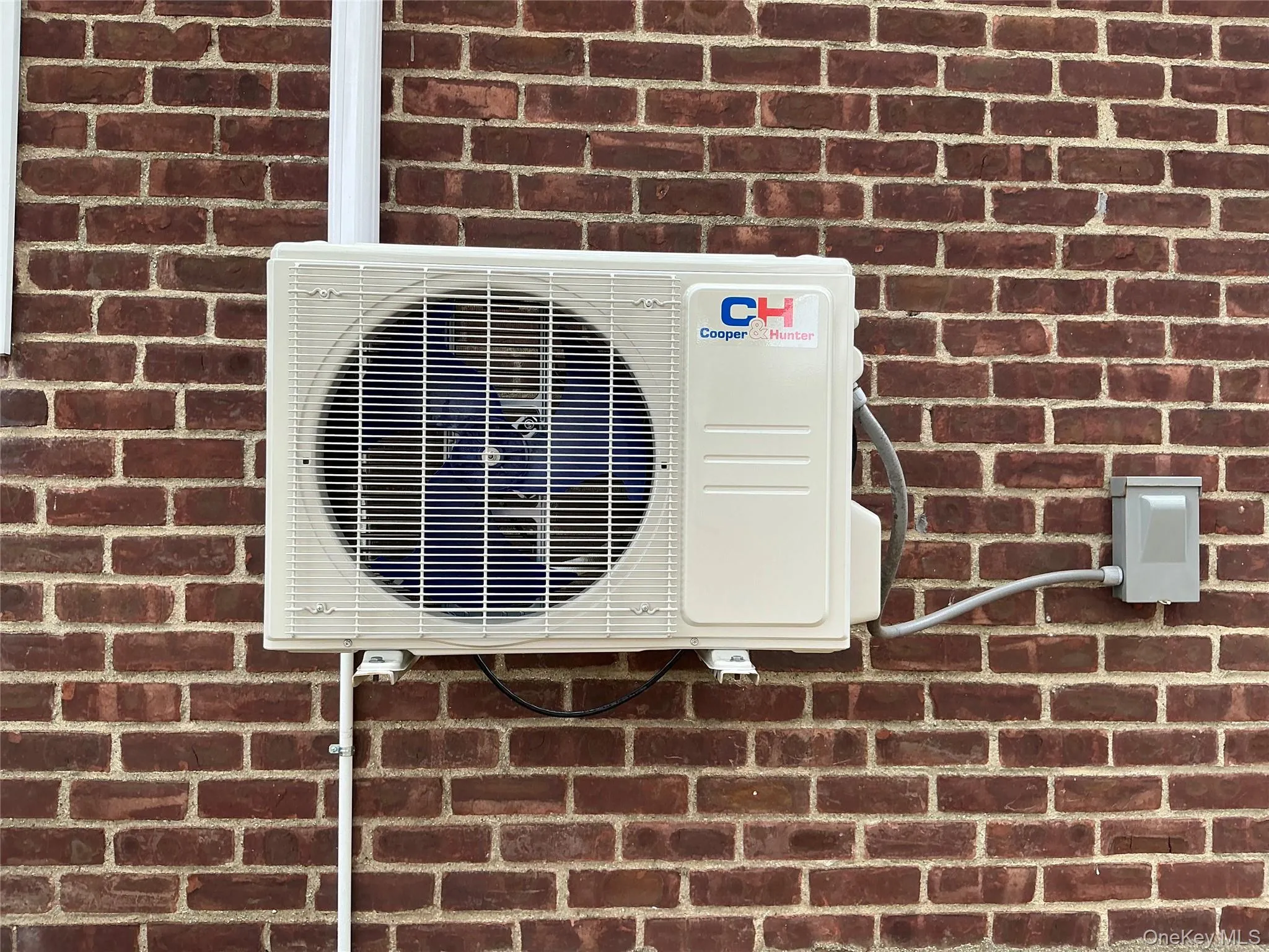 Detailed view of a cooling unit and brick siding Detailed view of a cooling unit and brick siding