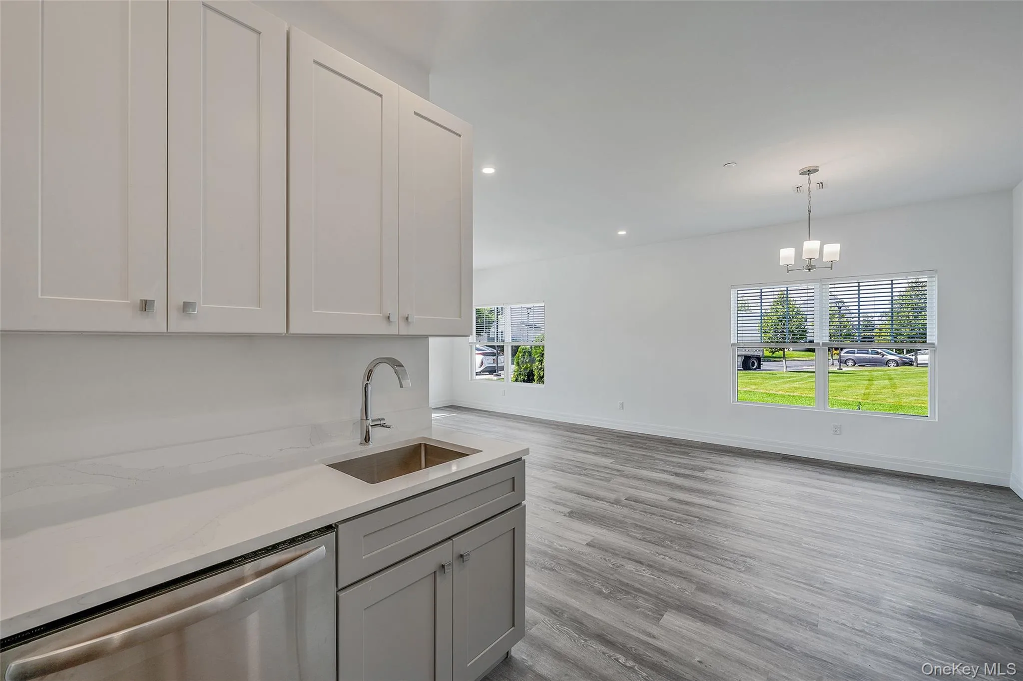 Kitchen with stainless steel dishwasher, recessed lighting, light stone counters, light wood-style floors, and hanging light fixtures Kitchen with stainless steel dishwasher, recessed lighting, light stone counters, light wood-style floors, and hanging light fixtures