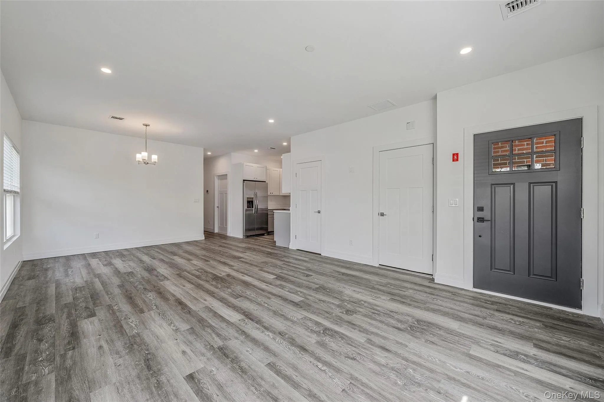 Unfurnished living room featuring recessed lighting, light wood-style flooring, and a chandelier Unfurnished living room featuring recessed lighting, light wood-style flooring, and a chandelier