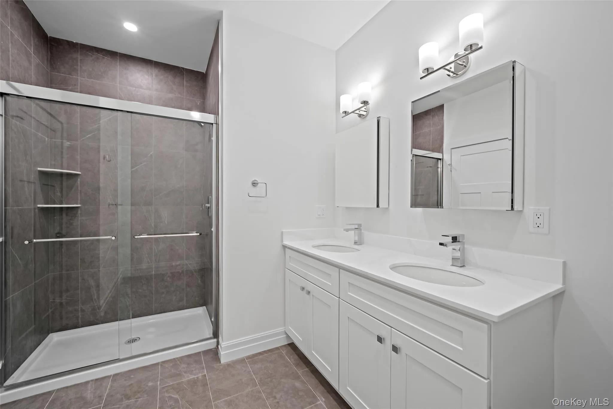 Full bath featuring double vanity, a shower stall, and light tile patterned floors Full bath featuring double vanity, a shower stall, and light tile patterned floors