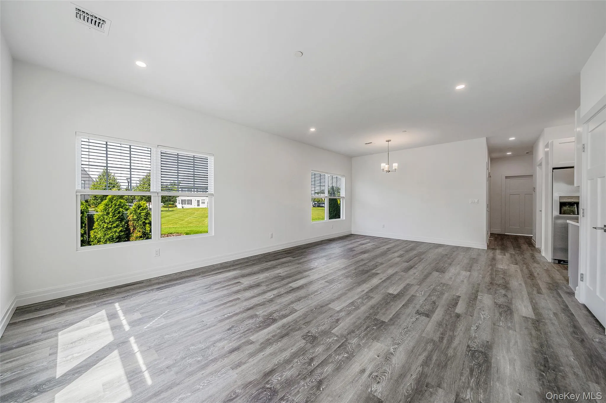 Unfurnished living room featuring recessed lighting, light wood-type flooring, and a chandelier Unfurnished living room featuring recessed lighting, light wood-type flooring, and a chandelier