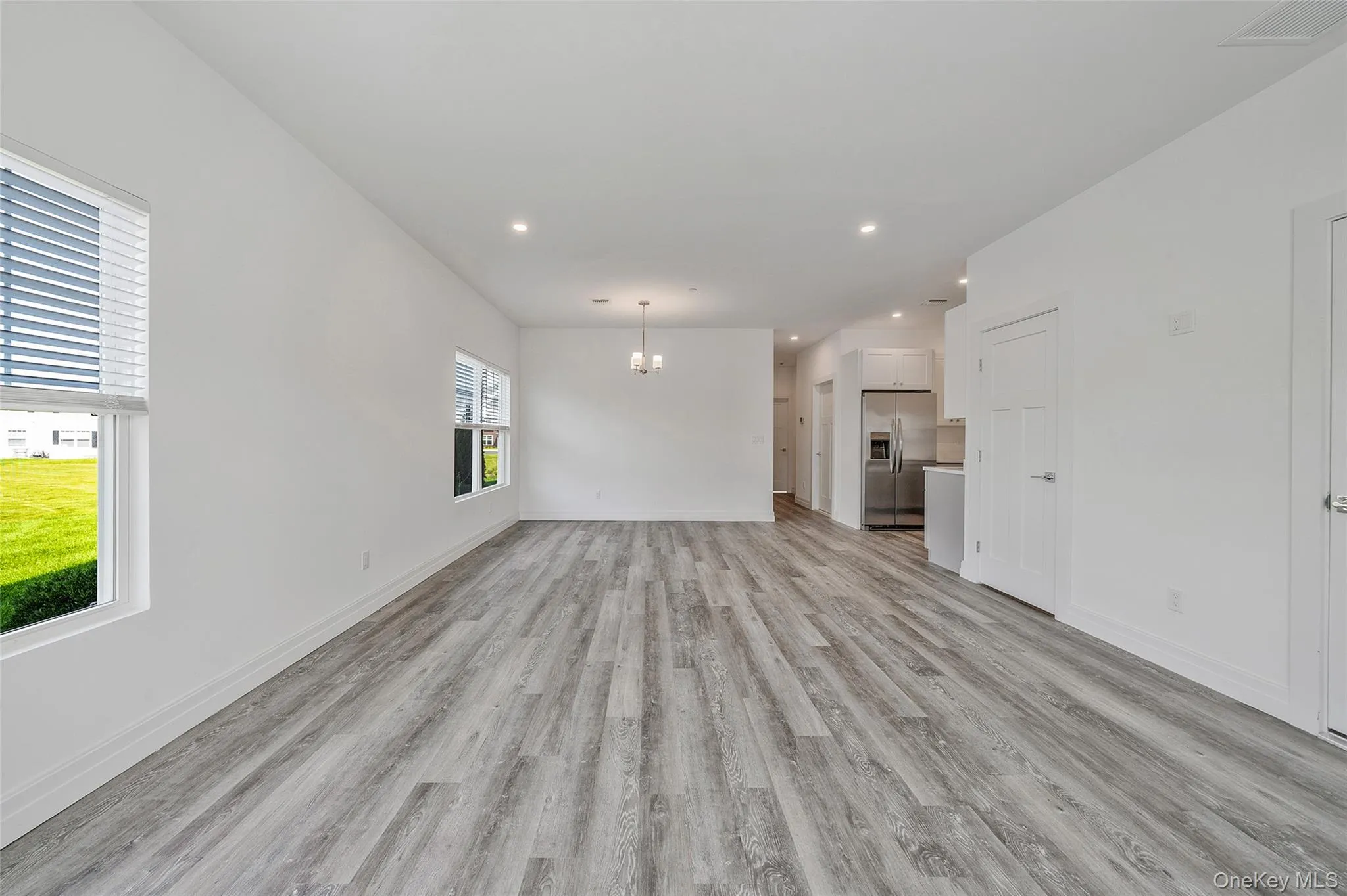 Unfurnished living room featuring a chandelier, recessed lighting, and light wood-style flooring Unfurnished living room featuring a chandelier, recessed lighting, and light wood-style flooring