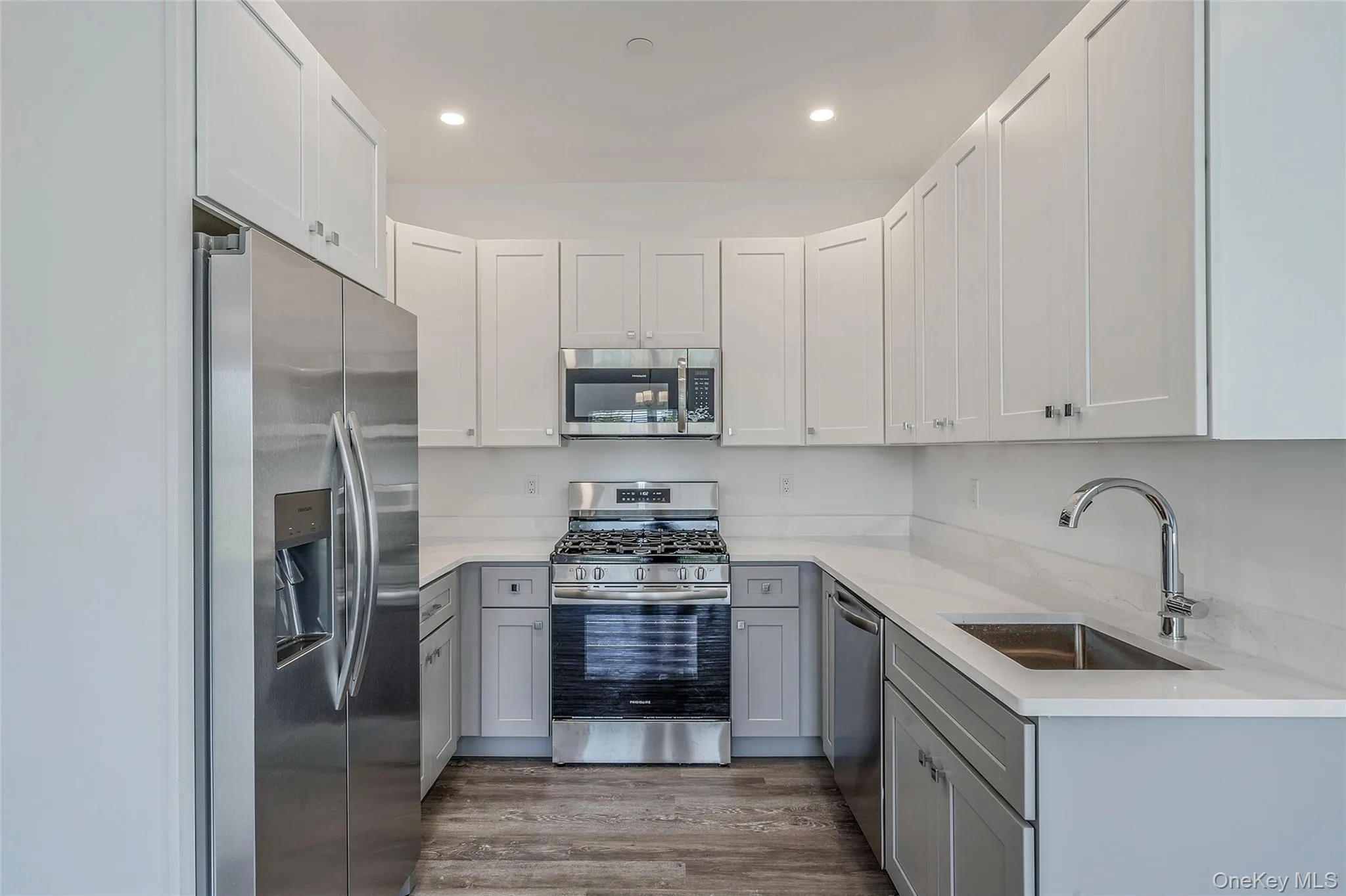 Kitchen featuring gray cabinetry, stainless steel appliances, light stone counters, white cabinetry, and dark wood-type flooring Kitchen featuring gray cabinetry, stainless steel appliances, light stone counters, white cabinetry, and dark wood-type flooring