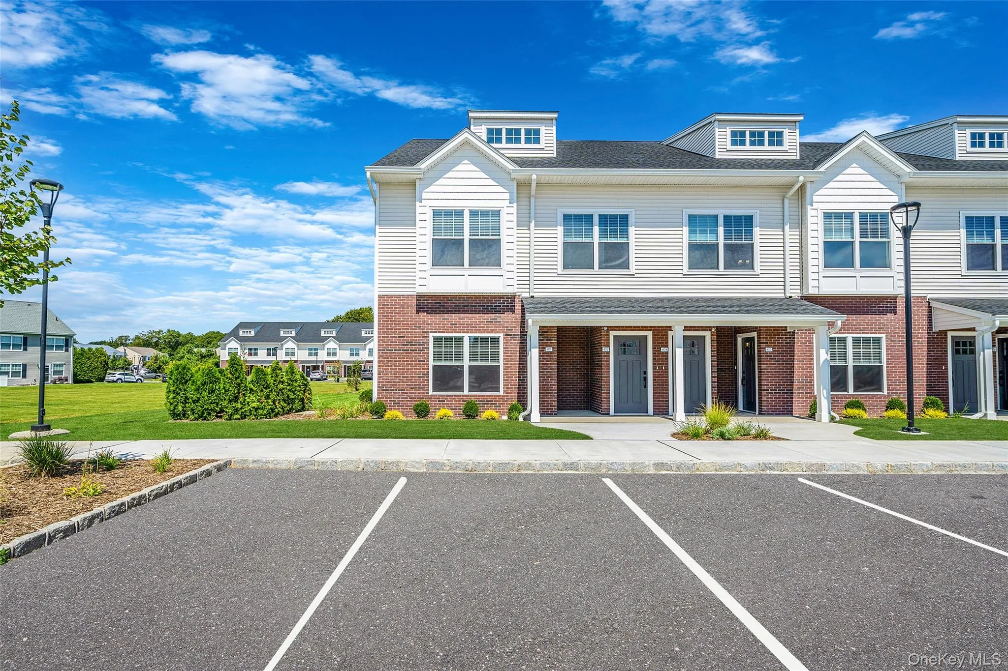 Traditional-style home featuring uncovered parking, brick siding, and a front yard Traditional-style home featuring uncovered parking, brick siding, and a front yard