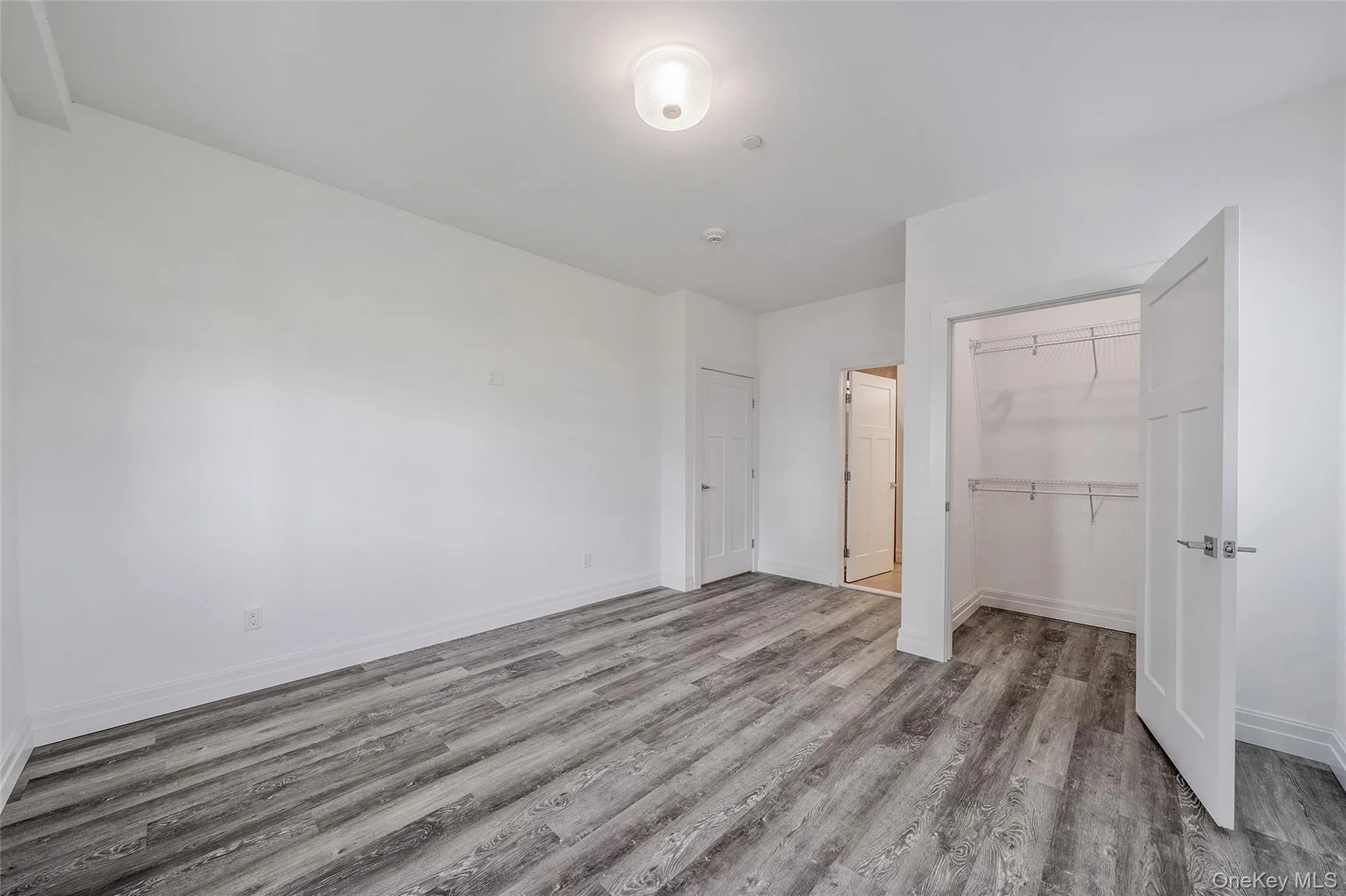 Unfurnished bedroom with light wood finished floors and baseboards Unfurnished bedroom with light wood finished floors and baseboards